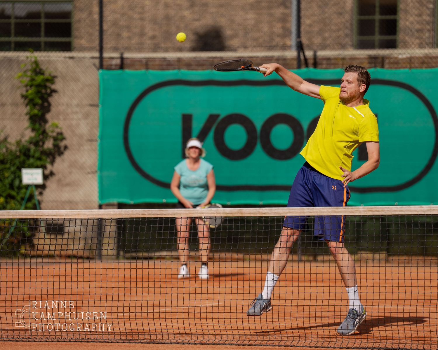 Actiefoto's van gravel tennistoernooi met spelers in actie, dubbelspel, toeschouwers en zomerse sfeer rond de baan.