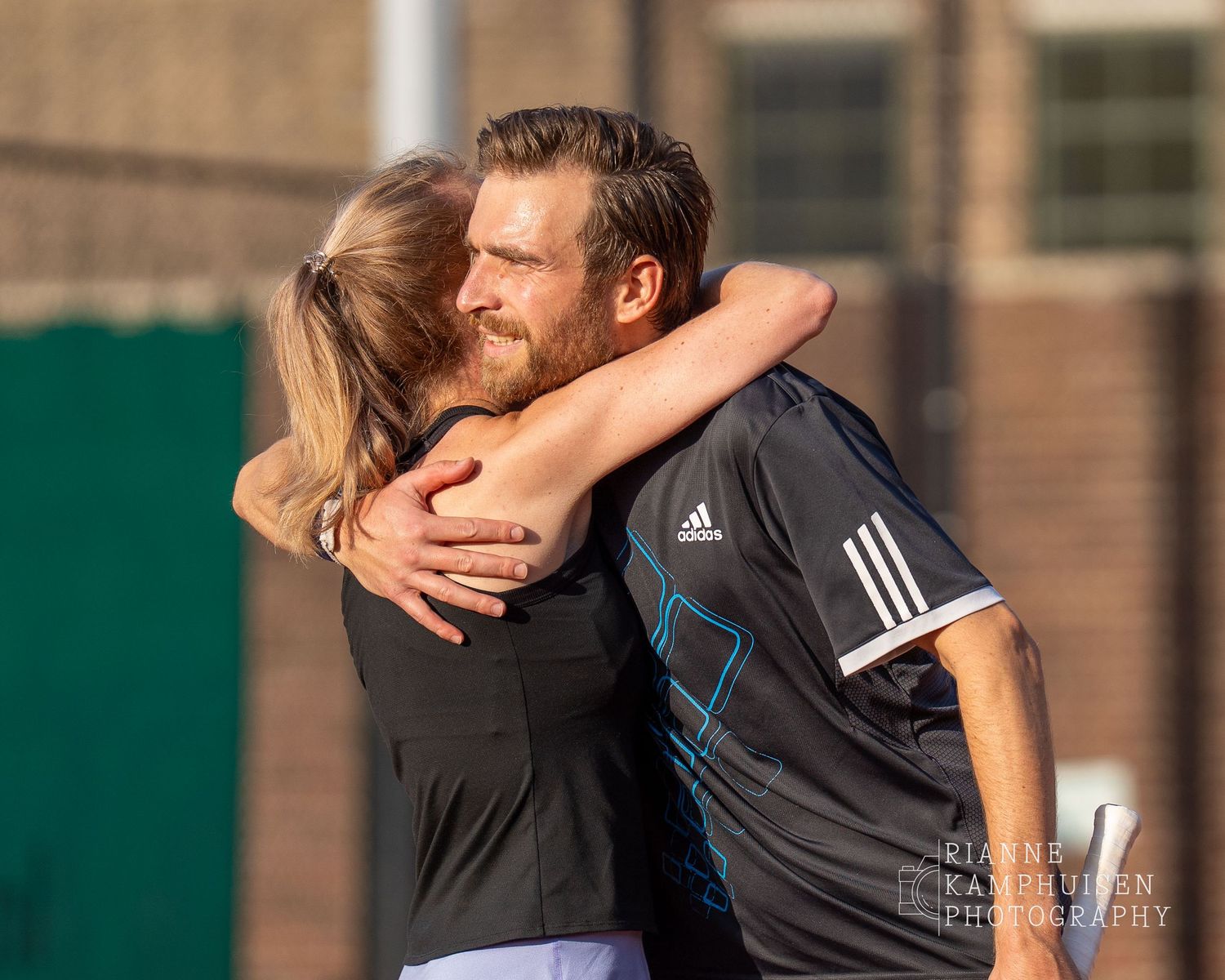 Actiefoto's van de vrijdagavond van een gravel tennistoernooi met spelers in actie, dubbelspel, toeschouwers en zomerse sfeer rond de baan.