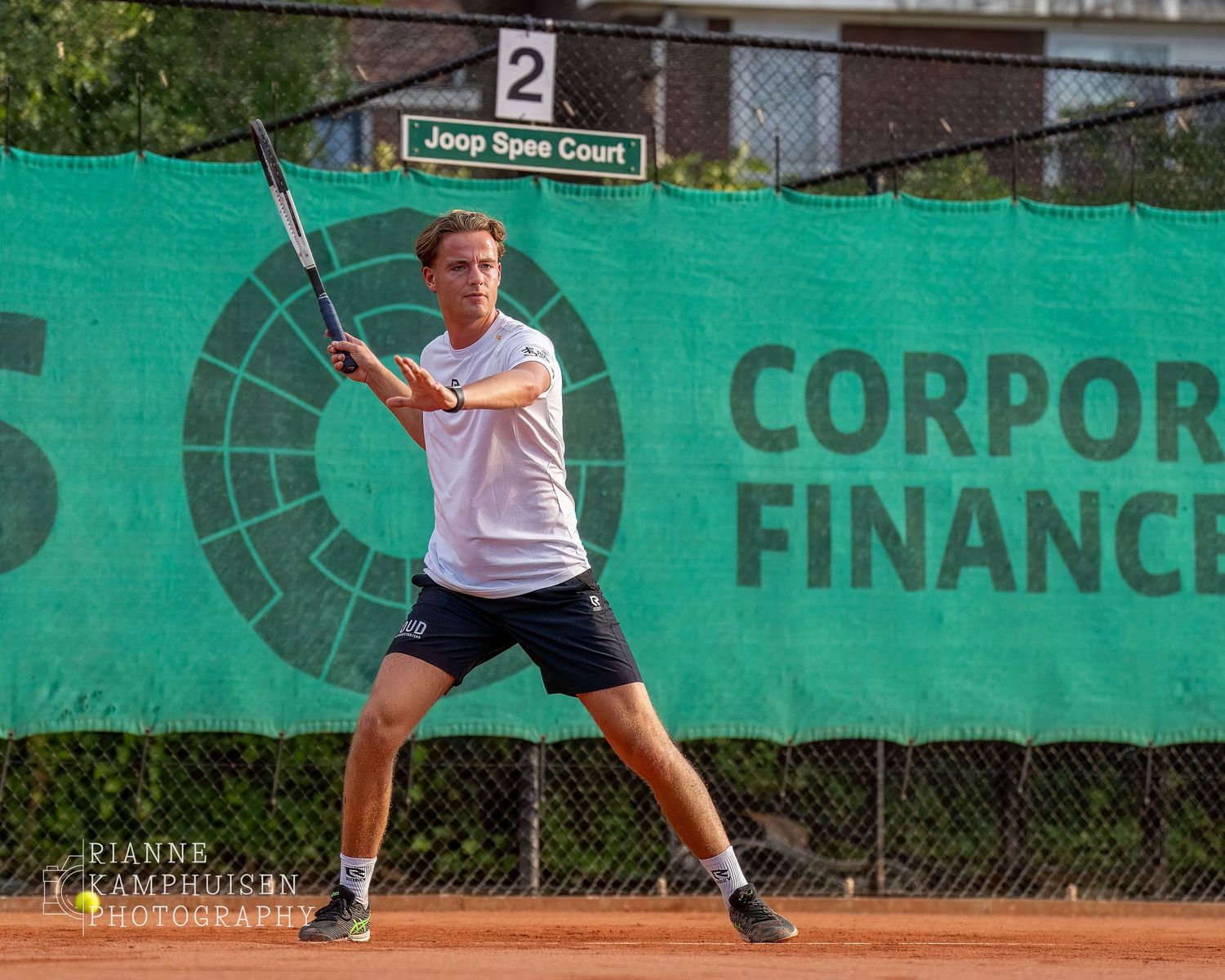 Actiefoto's van gravel tennistoernooi met spelers in actie, dubbelspel, toeschouwers en zomerse sfeer rond de baan.