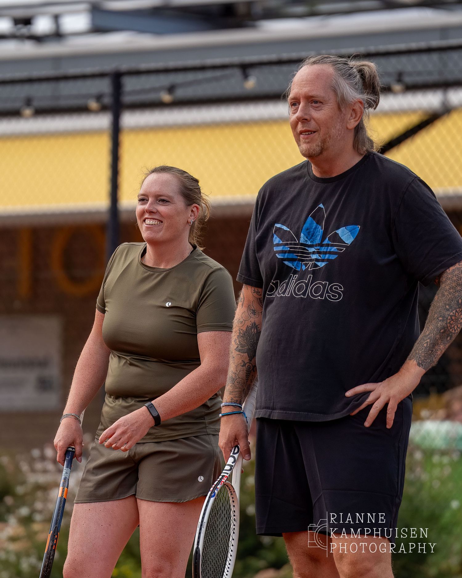 Actiefoto's van de vrijdagavond van een gravel tennistoernooi met spelers in actie, dubbelspel, toeschouwers en zomerse sfeer rond de baan.
