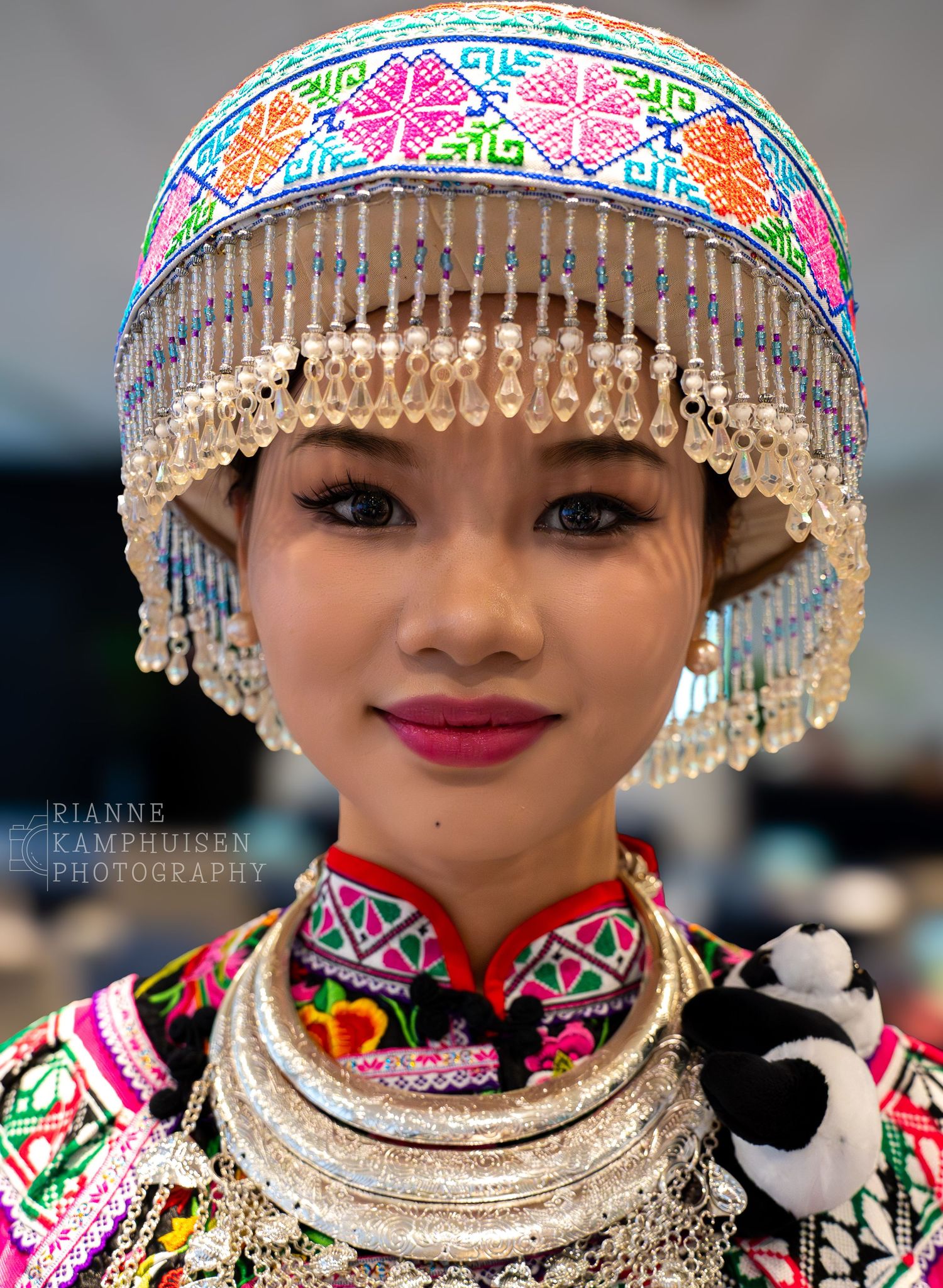 Portret van jonge vrouw in traditionele Chinese kleding met kleurrijke kralen en sieraden.