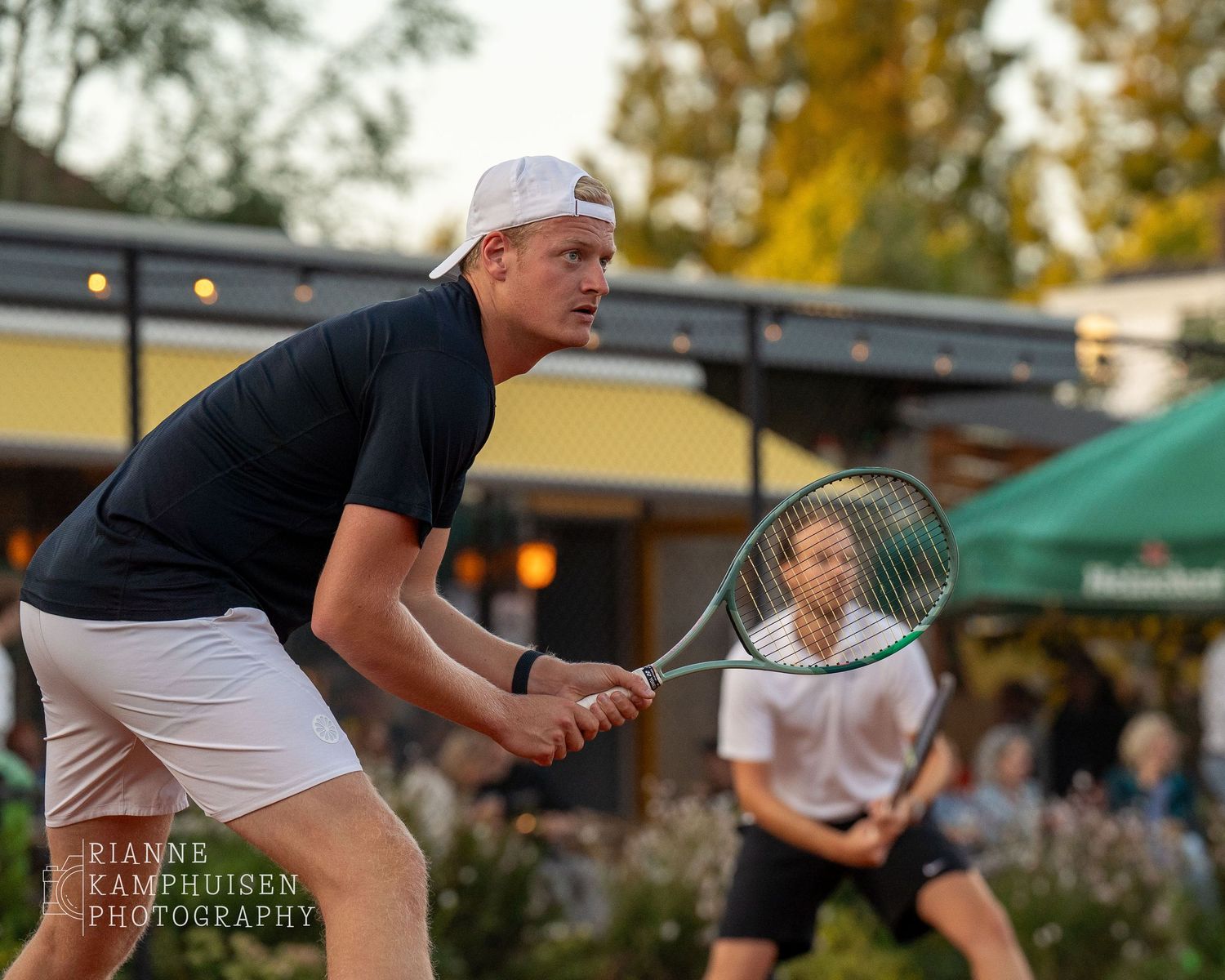 Actiefoto's van gravel tennistoernooi met spelers in actie, dubbelspel, toeschouwers en zomerse sfeer rond de baan.