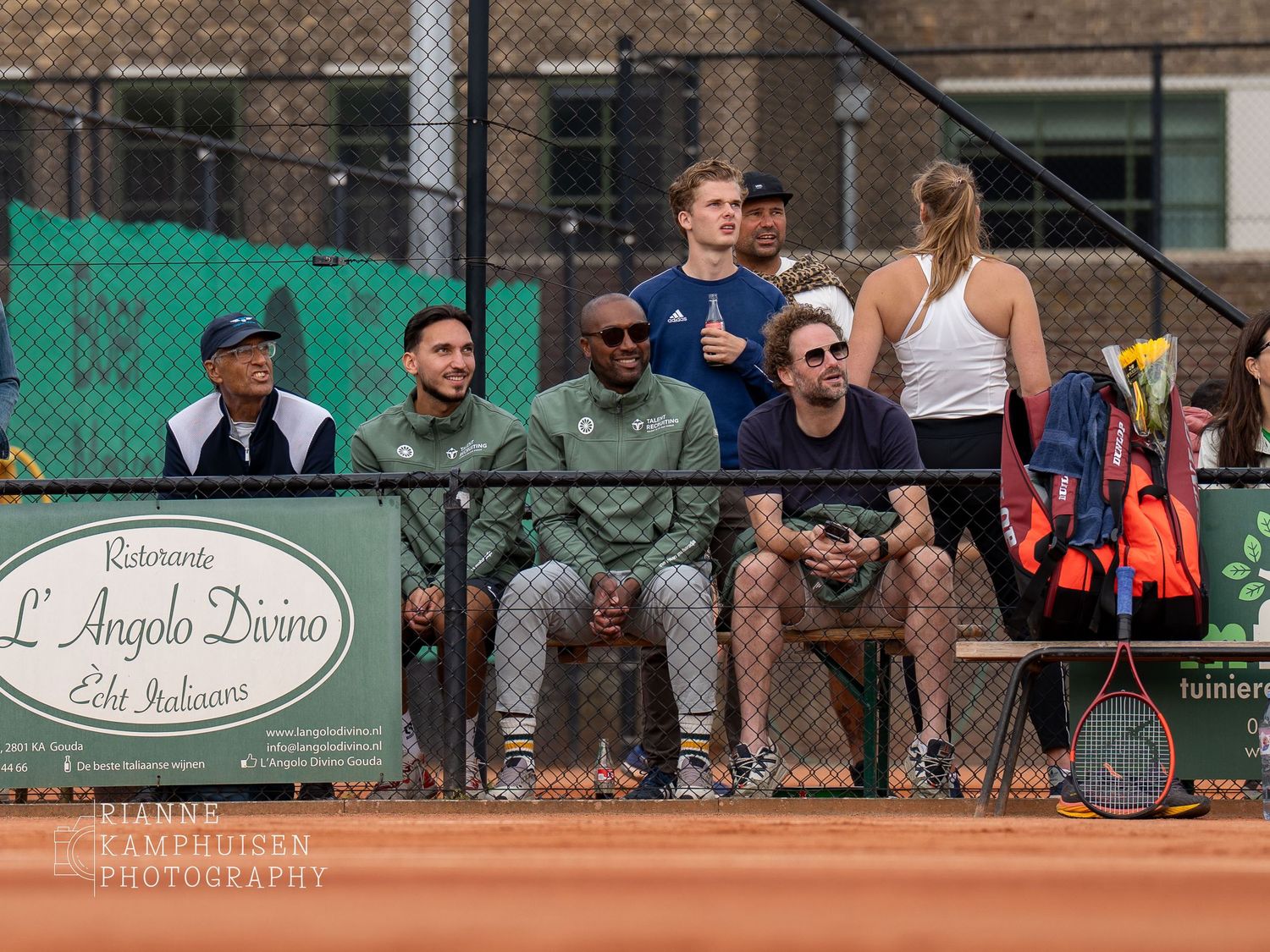 Actiefoto's en finalisten van een gravel tennistoernooi met spelers in actie, dubbelspel, toeschouwers en zomerse sfeer rond de baan.