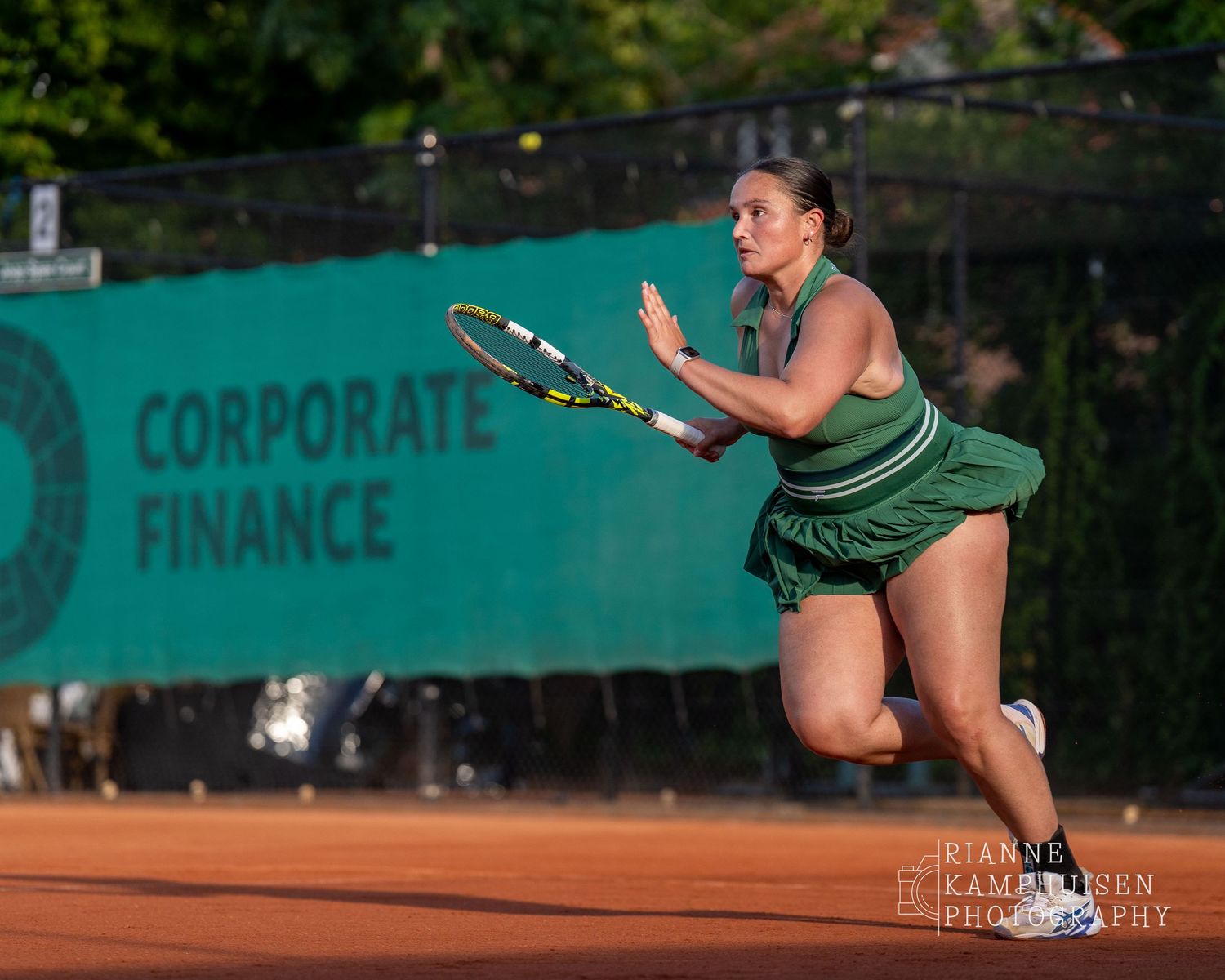 Actiefoto's van de woensdagavond van eengravel tennistoernooi met spelers in actie, dubbelspel, toeschouwers en zomerse sfeer rond de baan.