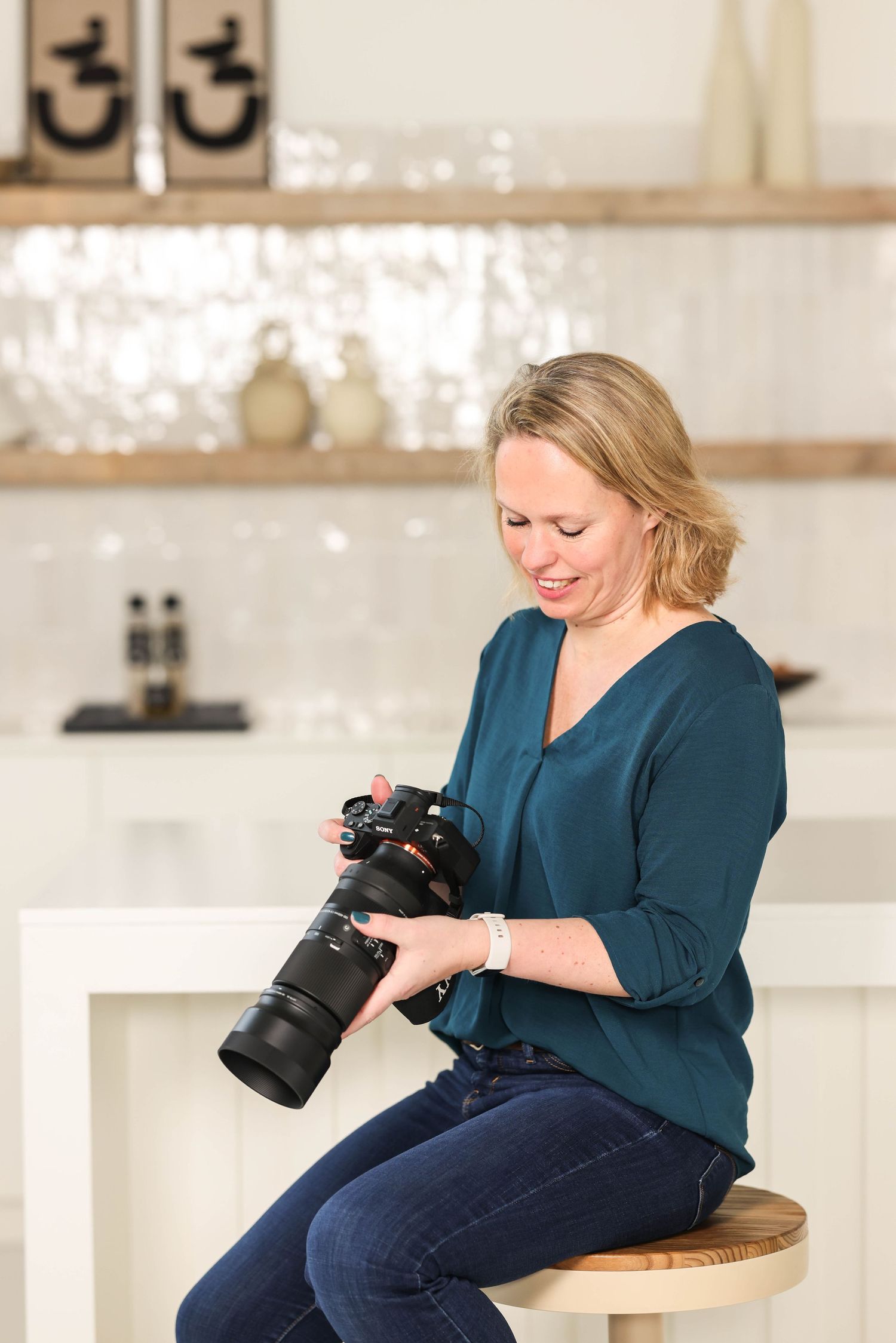 Rianne, de eigenaar van dit bedrijf, zit aan een keukenbar en kijkt in de camera terwijl er een grote zoomlens op de camera zit.