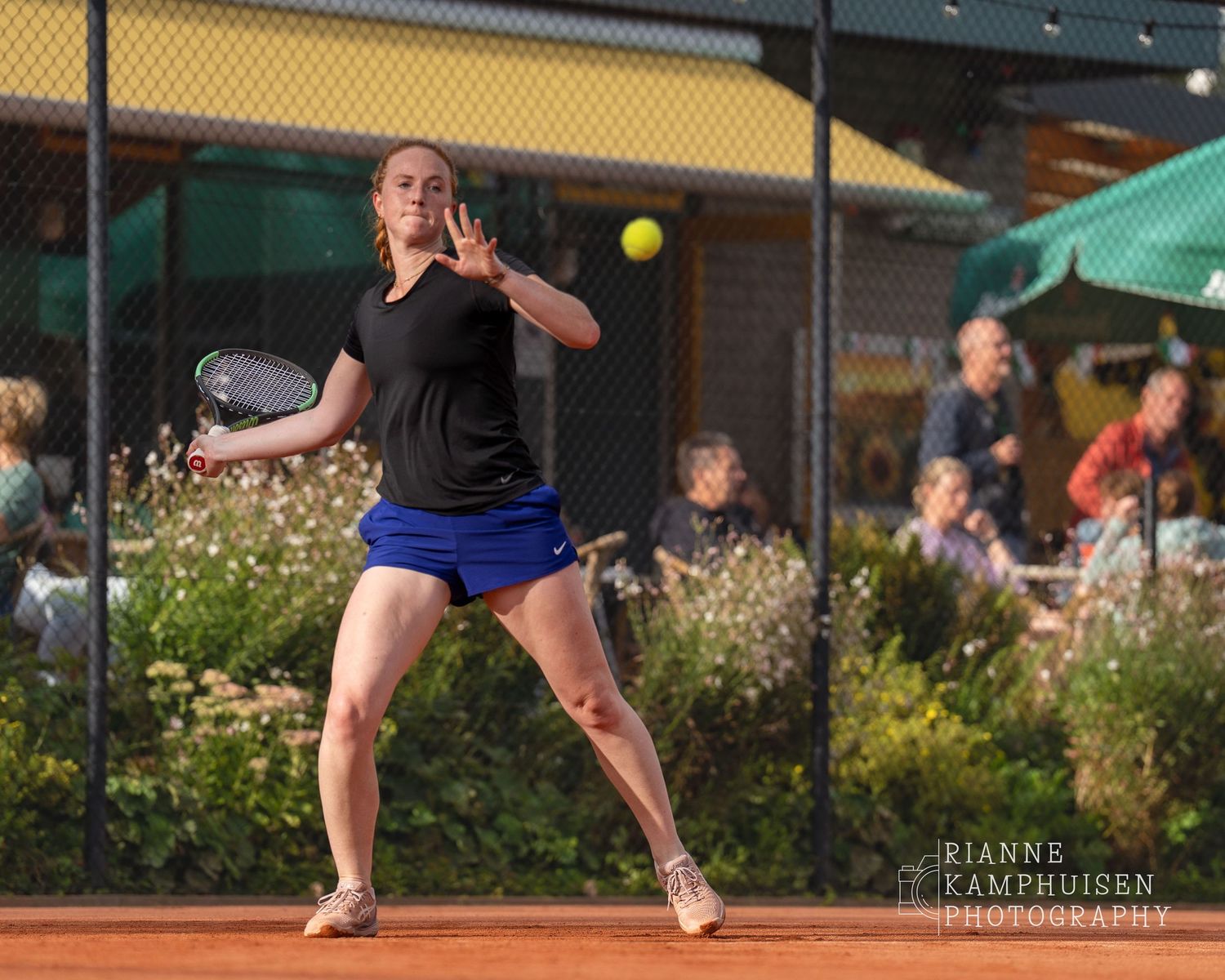 Actiefoto's van de vrijdagavond van een gravel tennistoernooi met spelers in actie, dubbelspel, toeschouwers en zomerse sfeer rond de baan.