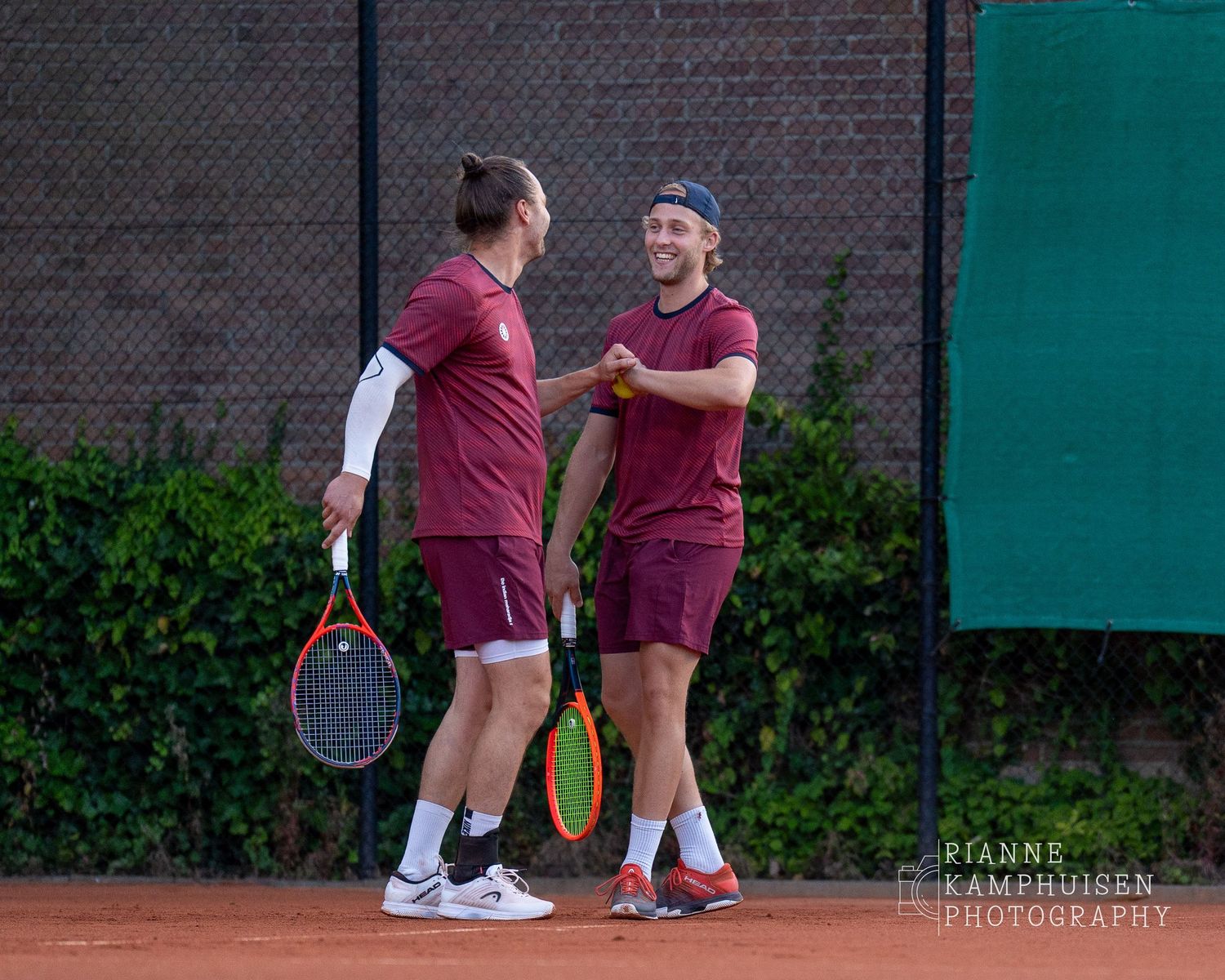 Actiefoto's van gravel tennistoernooi met spelers in actie, dubbelspel, toeschouwers en zomerse sfeer rond de baan.