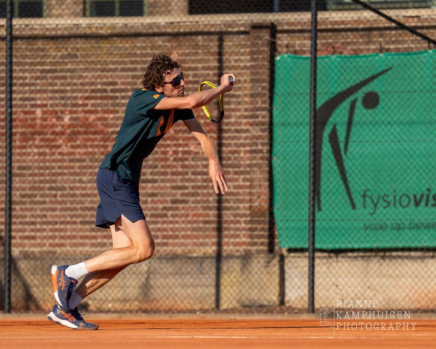 Actiefoto's van de woensdagavond van eengravel tennistoernooi met spelers in actie, dubbelspel, toeschouwers en zomerse sfeer rond de baan.v