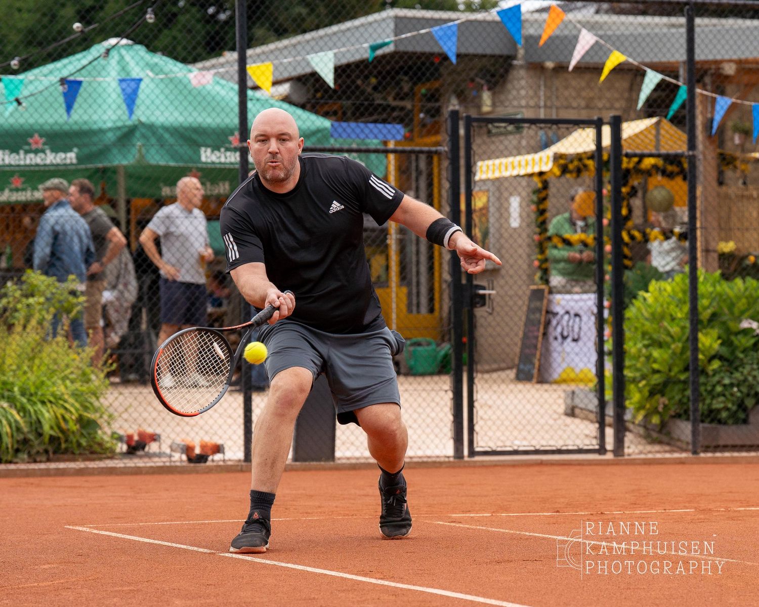 Actiefoto's van gravel tennistoernooi met spelers in actie, dubbelspel, toeschouwers en zomerse sfeer rond de baan.