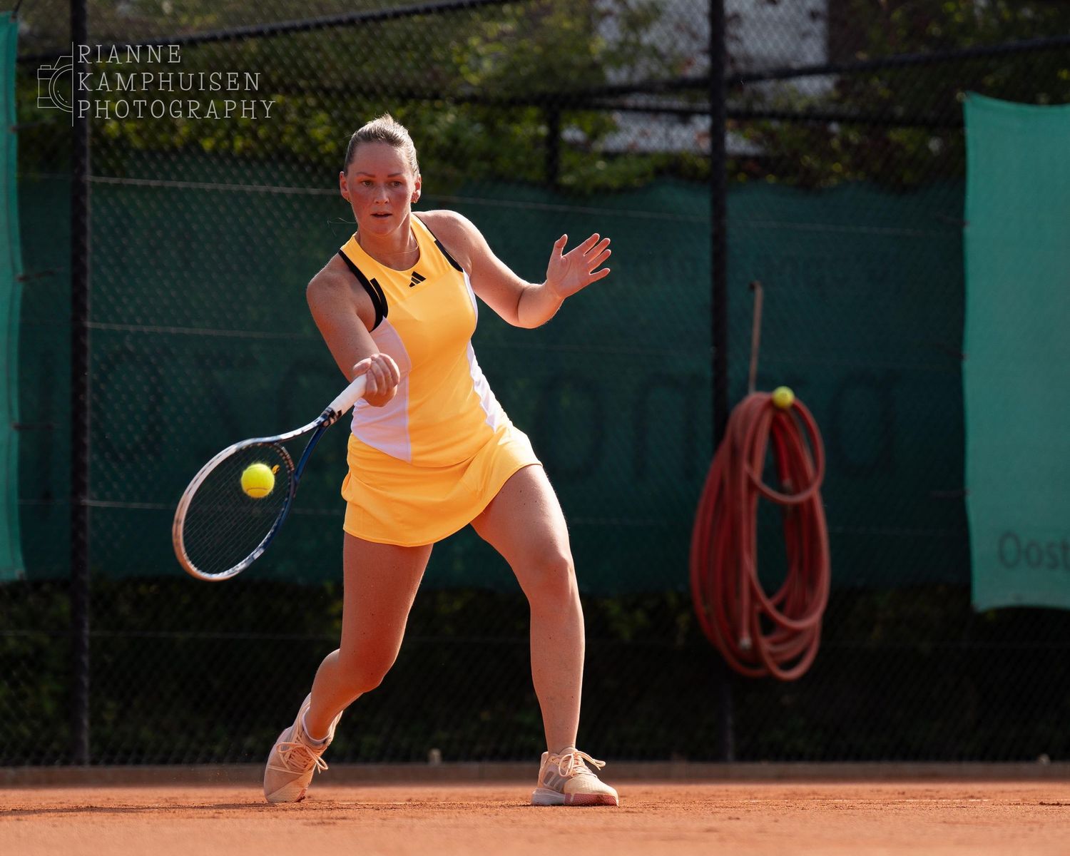 Actiefoto's van gravel tennistoernooi met spelers in actie, dubbelspel, toeschouwers en zomerse sfeer rond de baan.