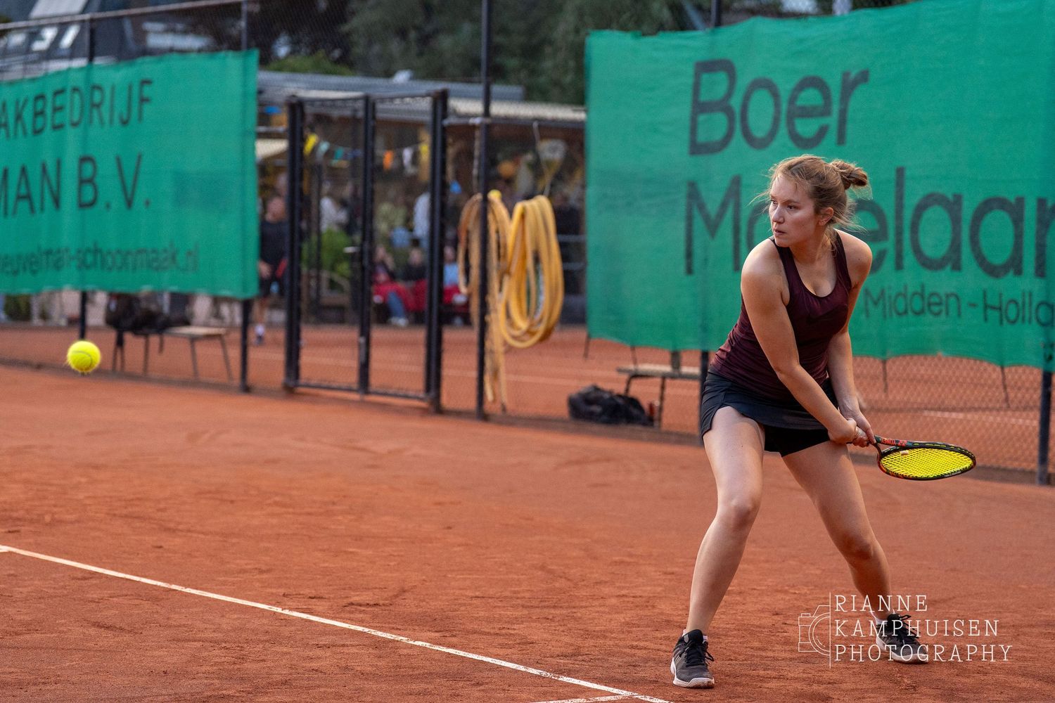 Actiefoto's van de vrijdagavond van een gravel tennistoernooi met spelers in actie, dubbelspel, toeschouwers en zomerse sfeer rond de baan.