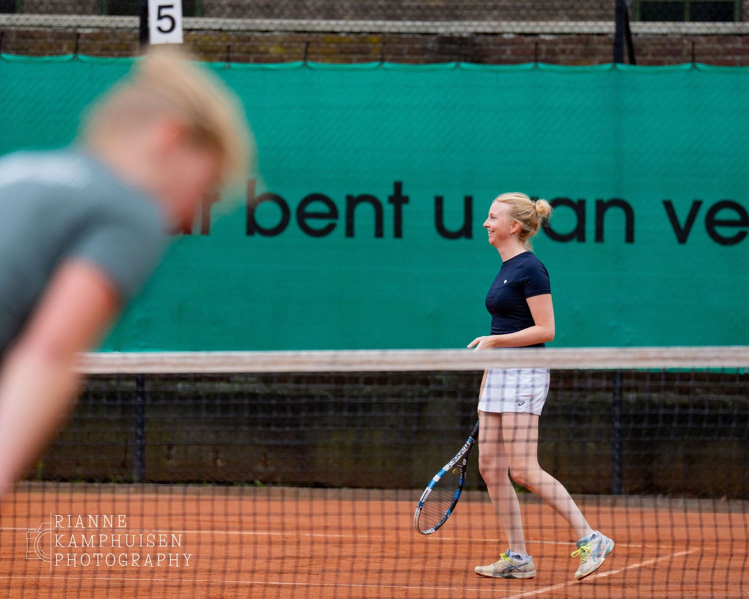 Actiefoto's van de zaterdag van een gravel tennistoernooi met spelers in actie, dubbelspel, toeschouwers en zomerse sfeer rond de baan.