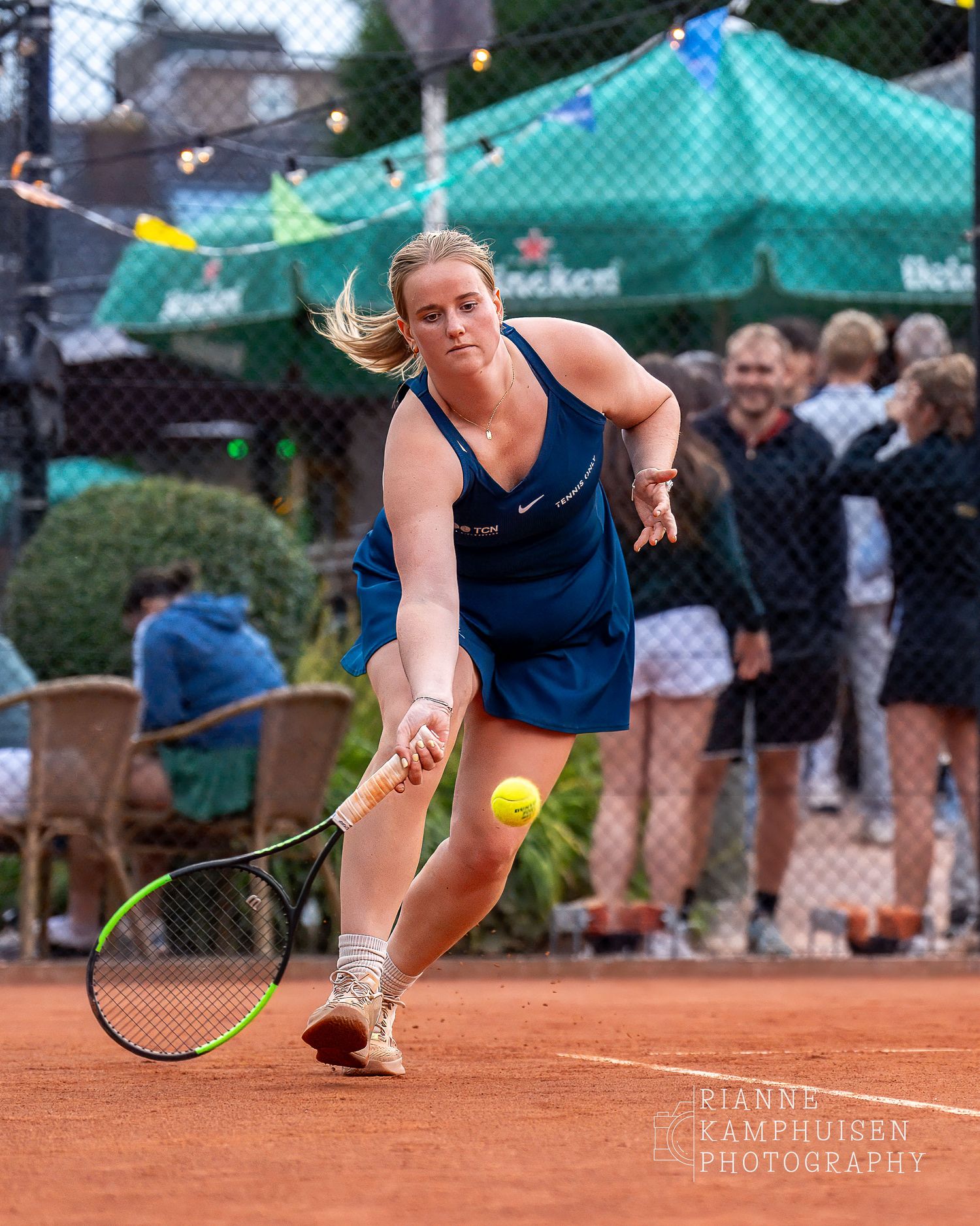 Actiefoto's van de woensdagavond van eengravel tennistoernooi met spelers in actie, dubbelspel, toeschouwers en zomerse sfeer rond de baan.