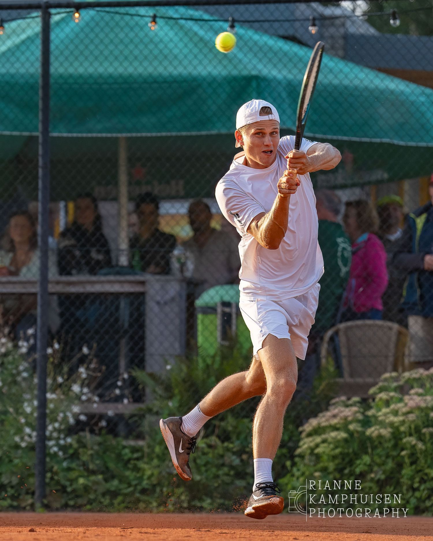 Actiefoto's van de woensdagavond van eengravel tennistoernooi met spelers in actie, dubbelspel, toeschouwers en zomerse sfeer rond de baan.