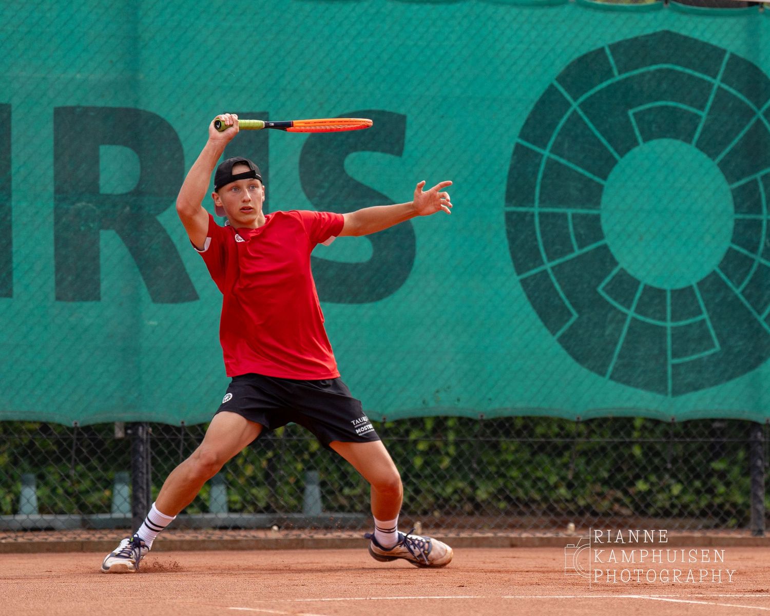 Actiefoto's van de vrijdagavond van een gravel tennistoernooi met spelers in actie, dubbelspel, toeschouwers en zomerse sfeer rond de baan.