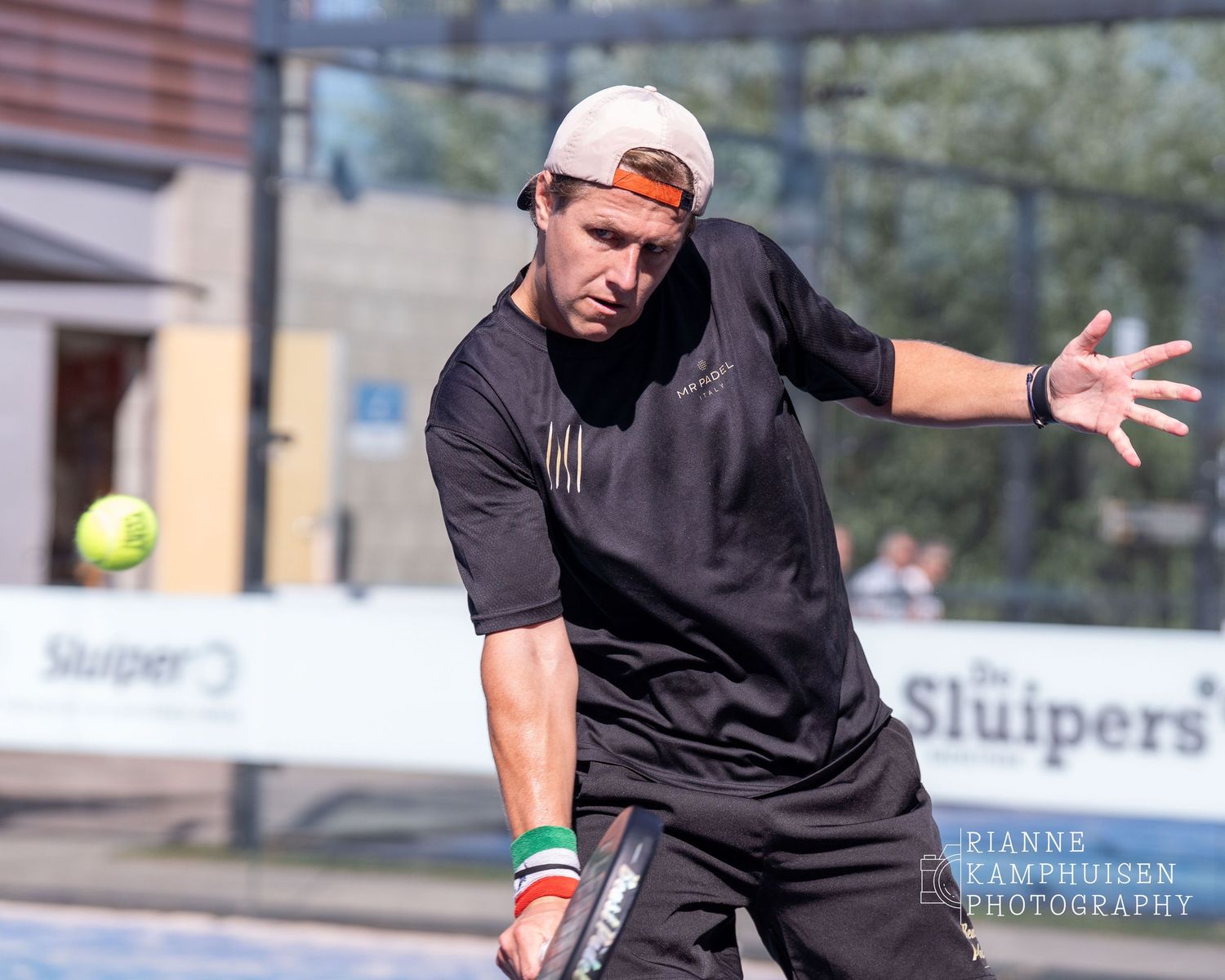Padelspeler kijkt gefocust naar de bal die hij met een backhand volley terug slaat