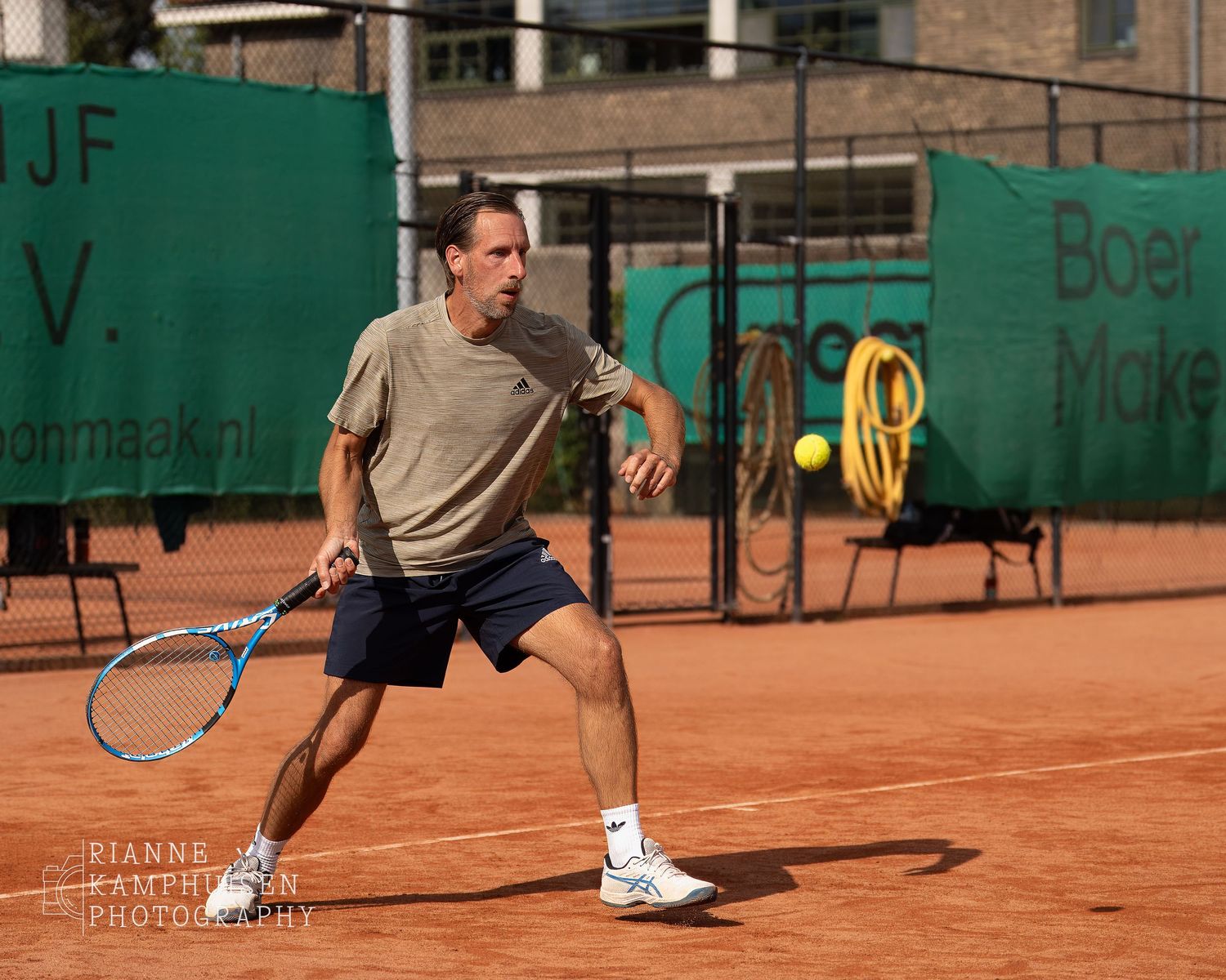 Actiefoto's van gravel tennistoernooi met spelers in actie, dubbelspel, toeschouwers en zomerse sfeer rond de baan.