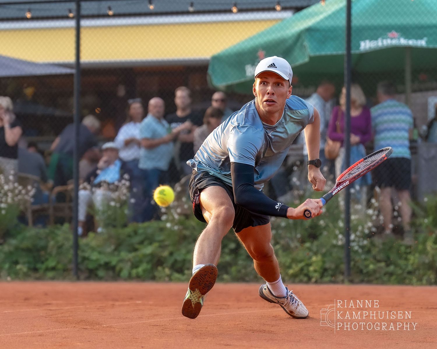 Actiefoto's van de woensdagavond van eengravel tennistoernooi met spelers in actie, dubbelspel, toeschouwers en zomerse sfeer rond de baan.