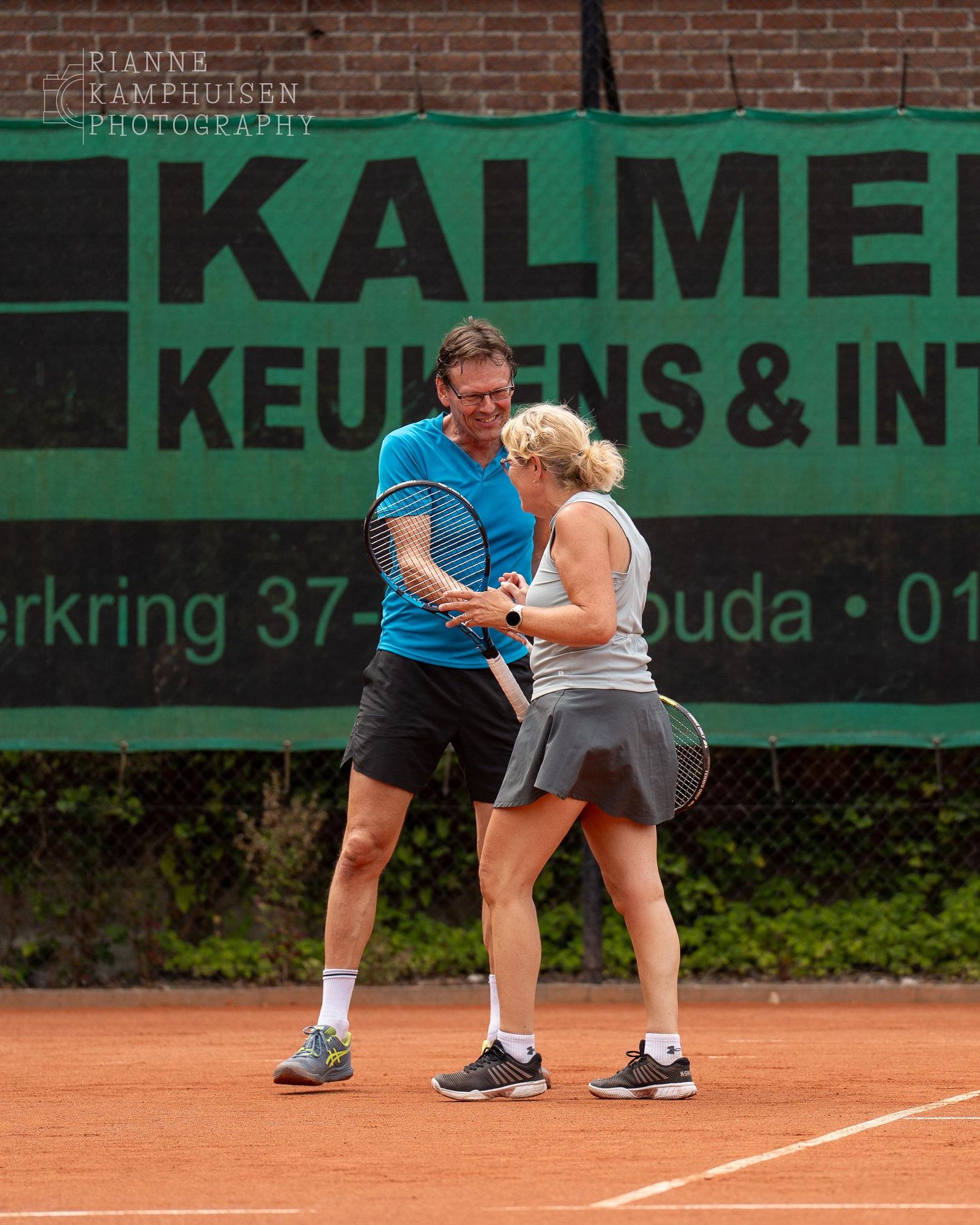 Actiefoto's van gravel tennistoernooi met spelers in actie, dubbelspel, toeschouwers en zomerse sfeer rond de baan.