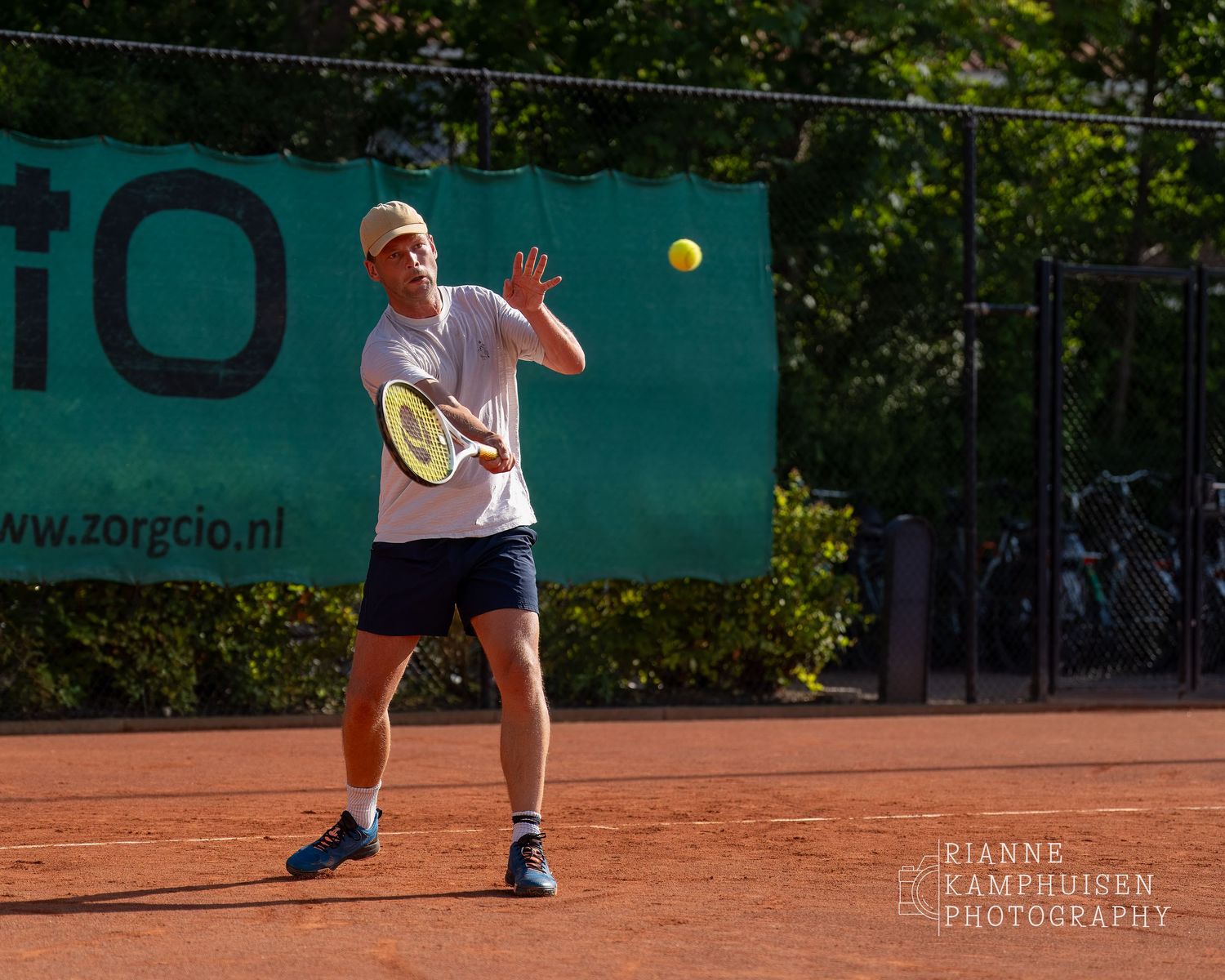 Actiefoto's van gravel tennistoernooi met spelers in actie, dubbelspel, toeschouwers en zomerse sfeer rond de baan.