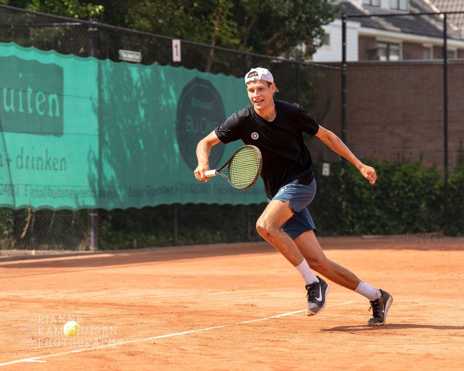 Actiefoto's en finalisten van een gravel tennistoernooi met spelers in actie, dubbelspel, toeschouwers en zomerse sfeer rond de baan.