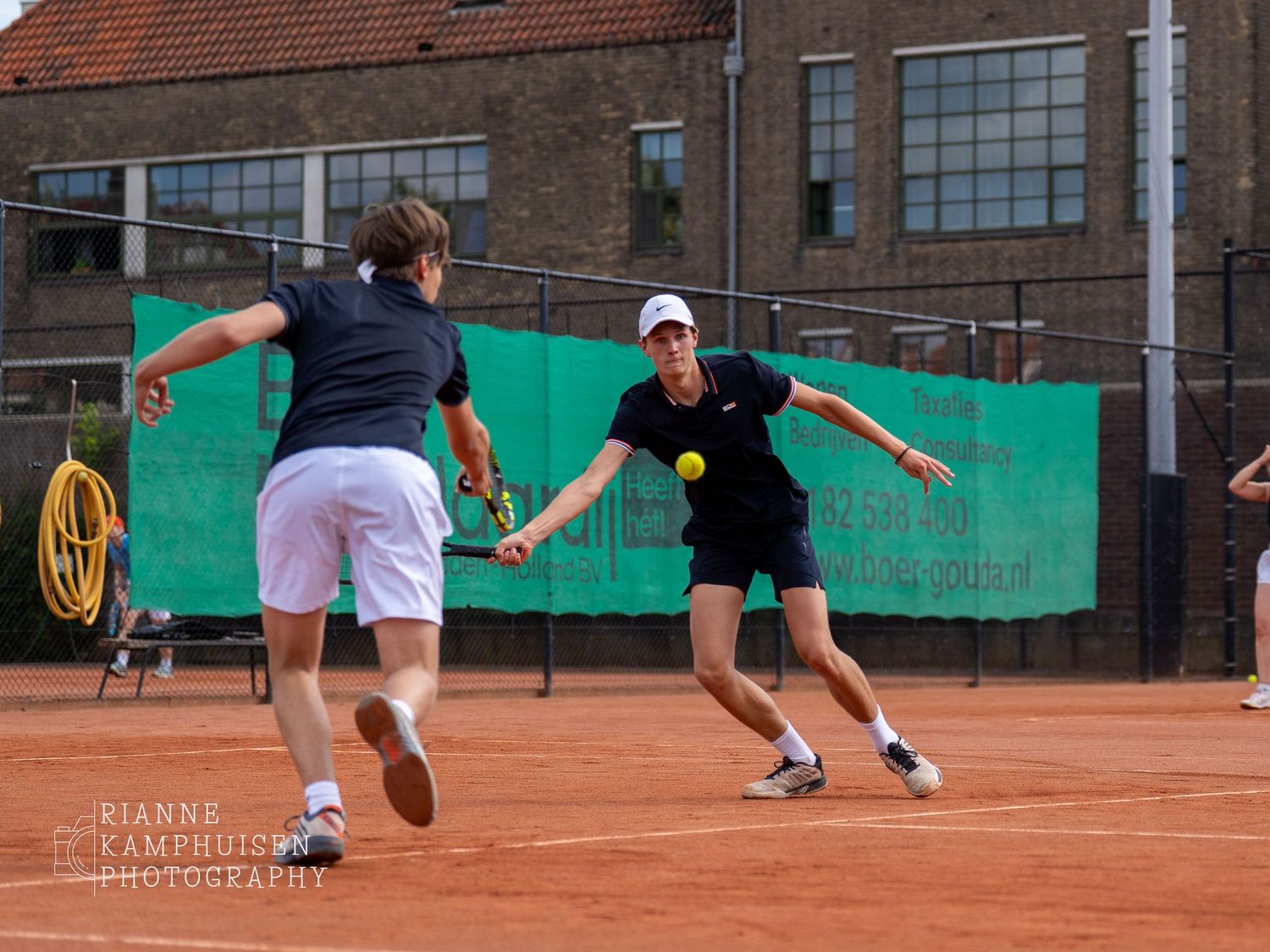 Actiefoto's en finalisten van een gravel tennistoernooi met spelers in actie, dubbelspel, toeschouwers en zomerse sfeer rond de baan.