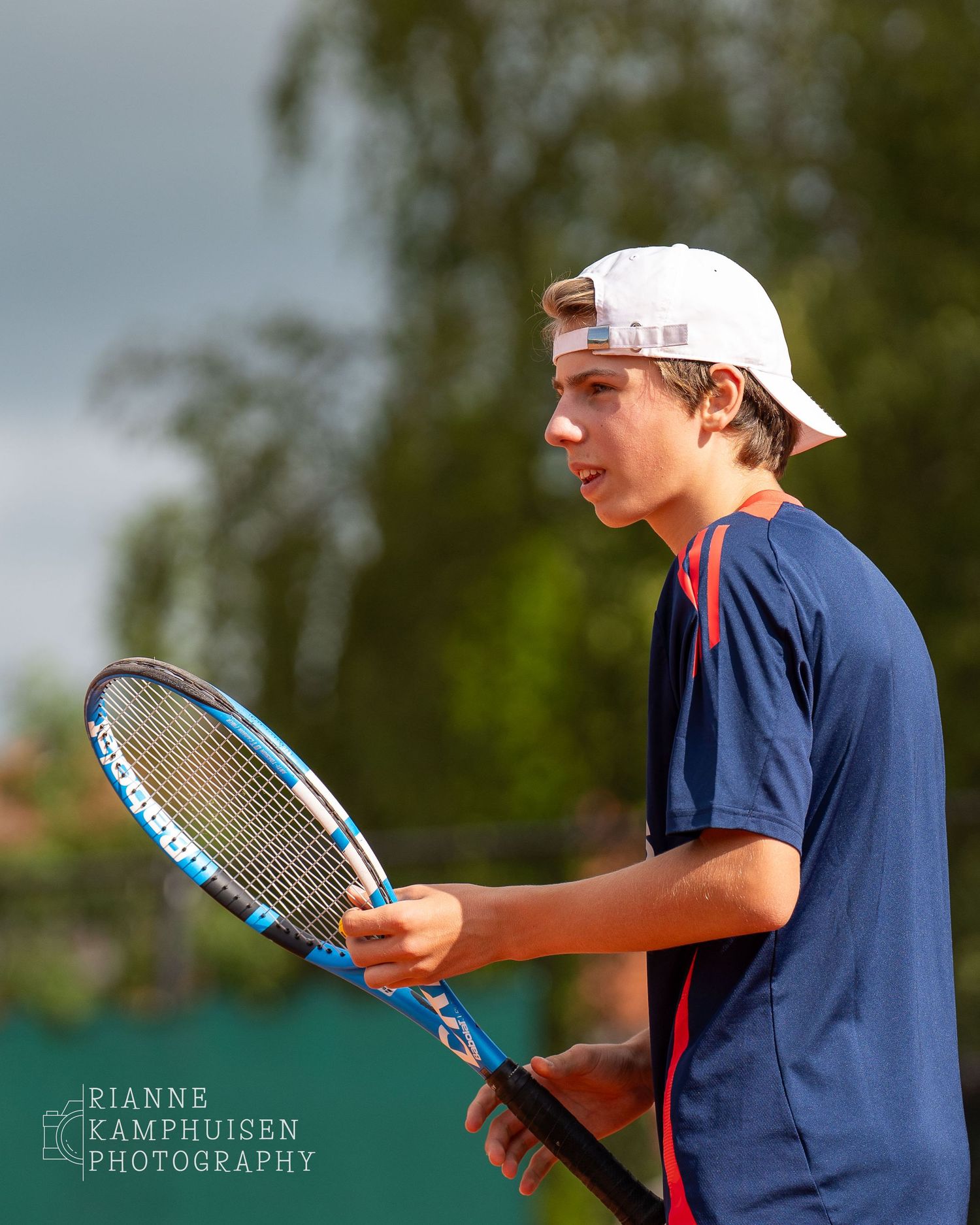 Actiefoto's van gravel tennistoernooi met spelers in actie, dubbelspel, toeschouwers en zomerse sfeer rond de baan.