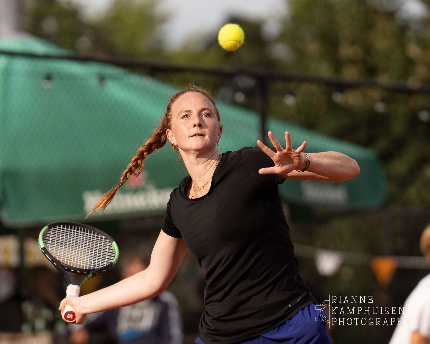 Actiefoto's van de vrijdagavond van een gravel tennistoernooi met spelers in actie, dubbelspel, toeschouwers en zomerse sfeer rond de baan.
