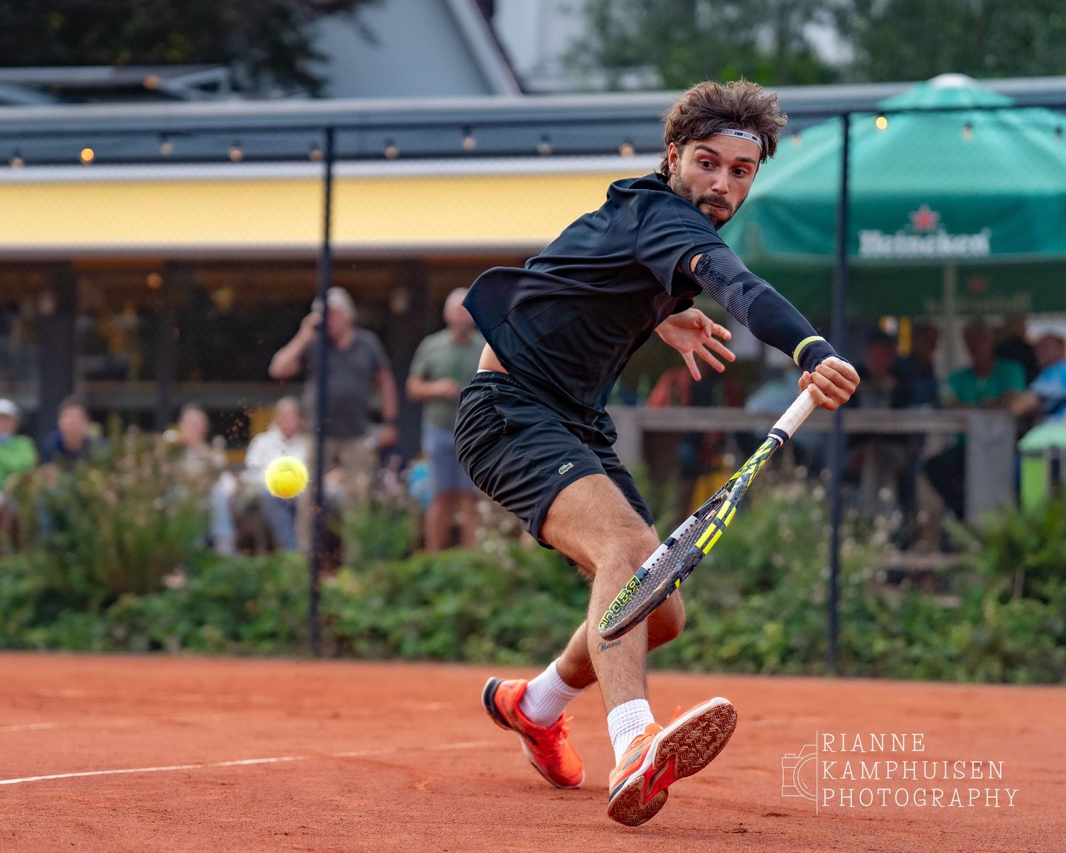 Actiefoto's van gravel tennistoernooi met spelers in actie, dubbelspel, toeschouwers en zomerse sfeer rond de baan.