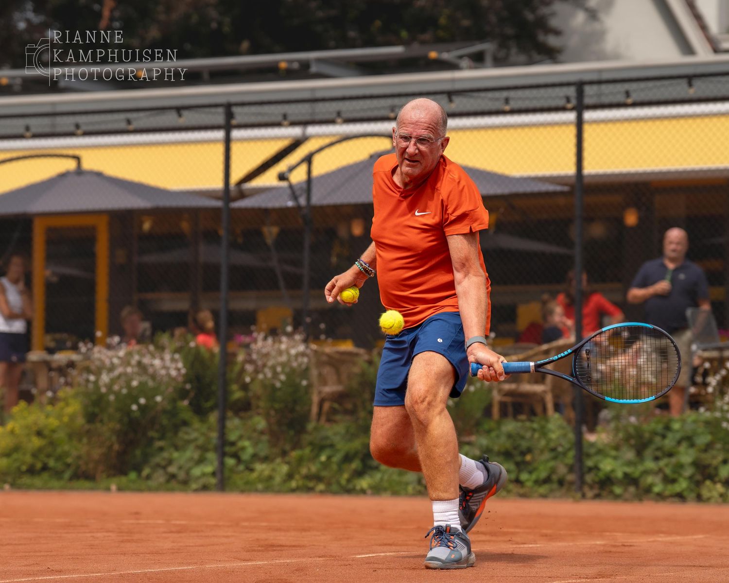 Actiefoto's van gravel tennistoernooi met spelers in actie, dubbelspel, toeschouwers en zomerse sfeer rond de baan.