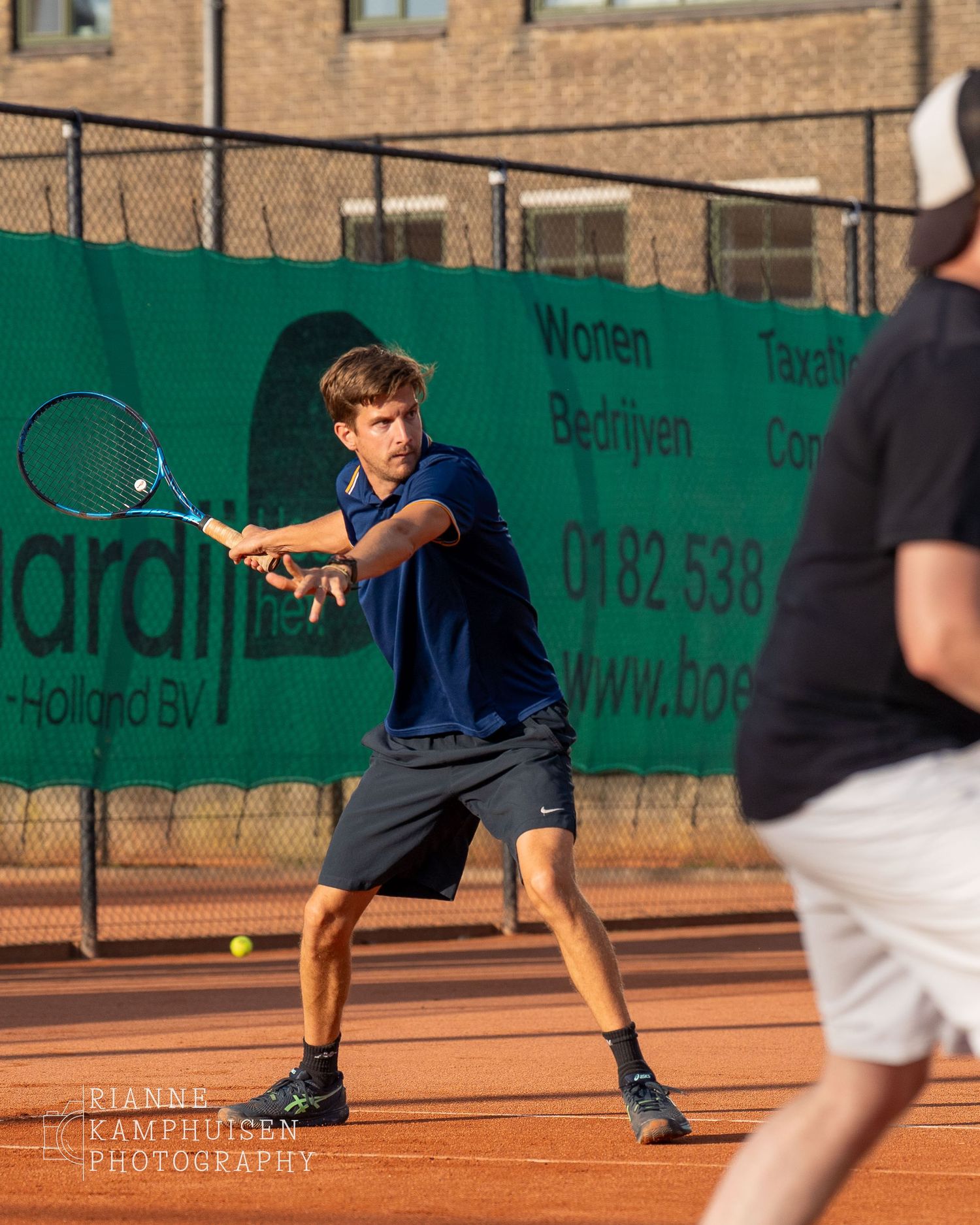 Actiefoto's van gravel tennistoernooi met spelers in actie, dubbelspel, toeschouwers en zomerse sfeer rond de baan.