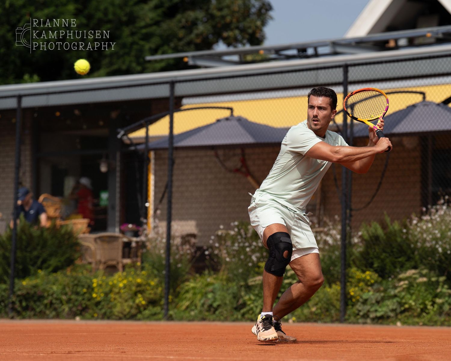 Actiefoto's van gravel tennistoernooi met spelers in actie, dubbelspel, toeschouwers en zomerse sfeer rond de baan.