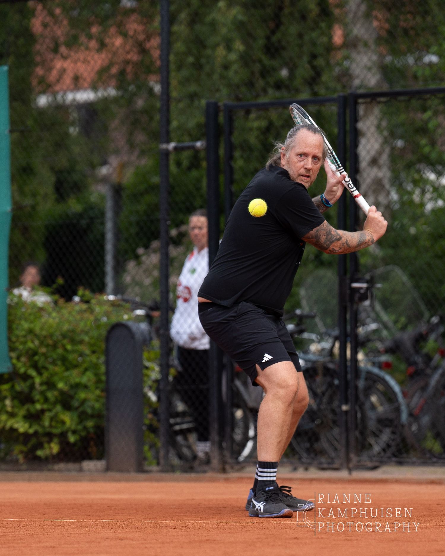 Actiefoto's van gravel tennistoernooi met spelers in actie, dubbelspel, toeschouwers en zomerse sfeer rond de baan.