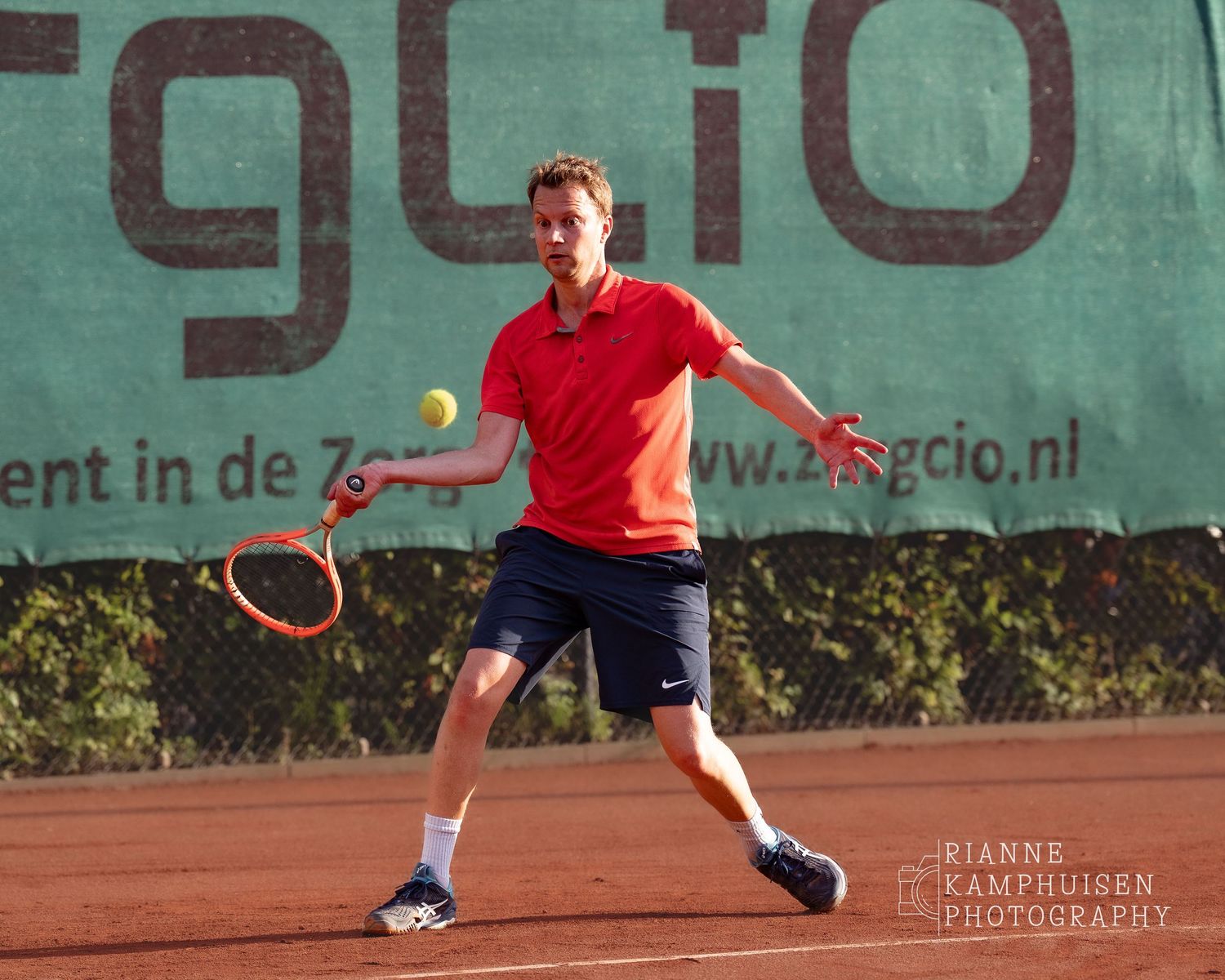 Actiefoto's van de vrijdagavond van een gravel tennistoernooi met spelers in actie, dubbelspel, toeschouwers en zomerse sfeer rond de baan.