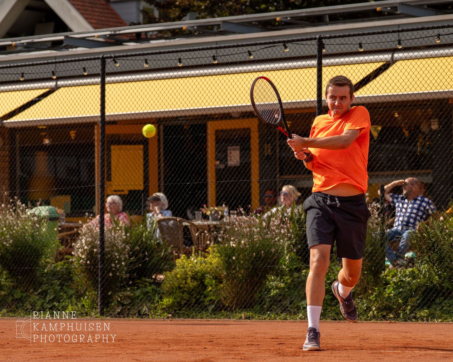 Actiefoto's van gravel tennistoernooi met spelers in actie, dubbelspel, toeschouwers en zomerse sfeer rond de baan.