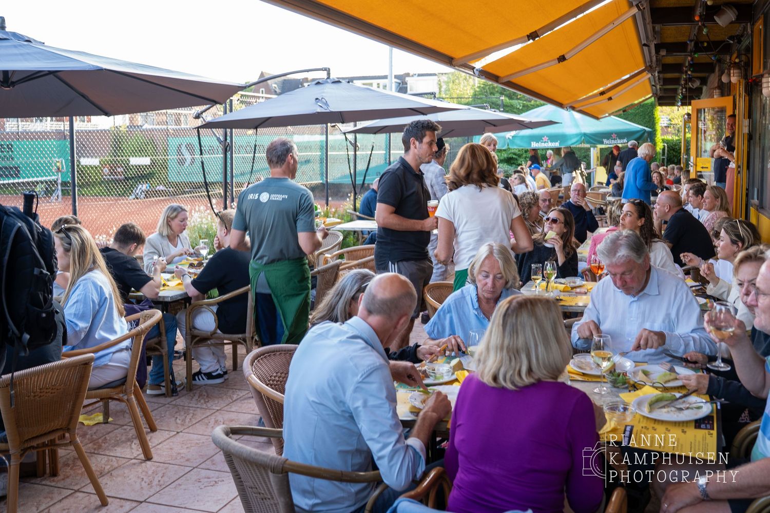 Actiefoto's van de woensdagavond van eengravel tennistoernooi met spelers in actie, dubbelspel, toeschouwers en zomerse sfeer rond de baan.