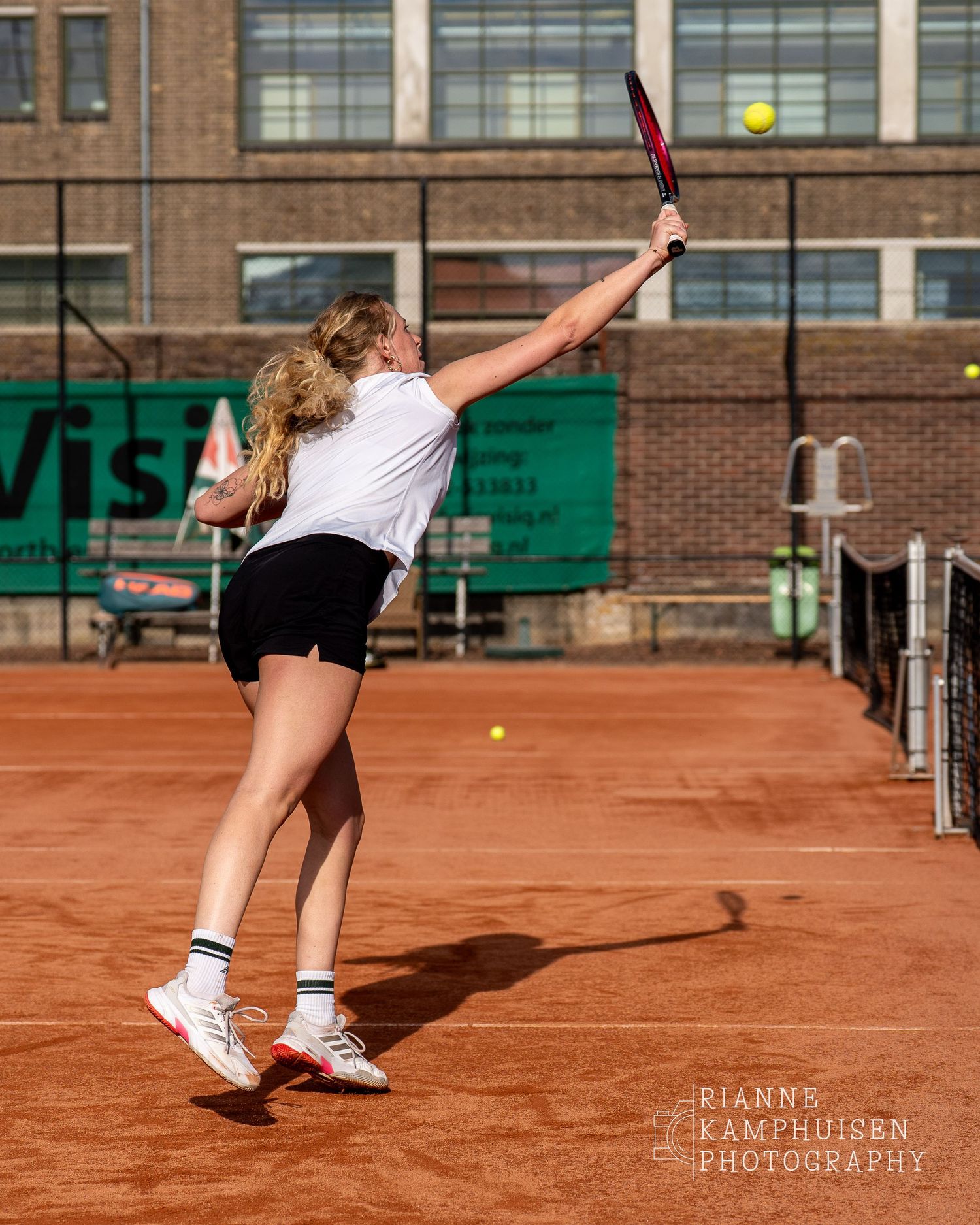 Actiefoto's van gravel tennistoernooi met spelers in actie, dubbelspel, toeschouwers en zomerse sfeer rond de baan.