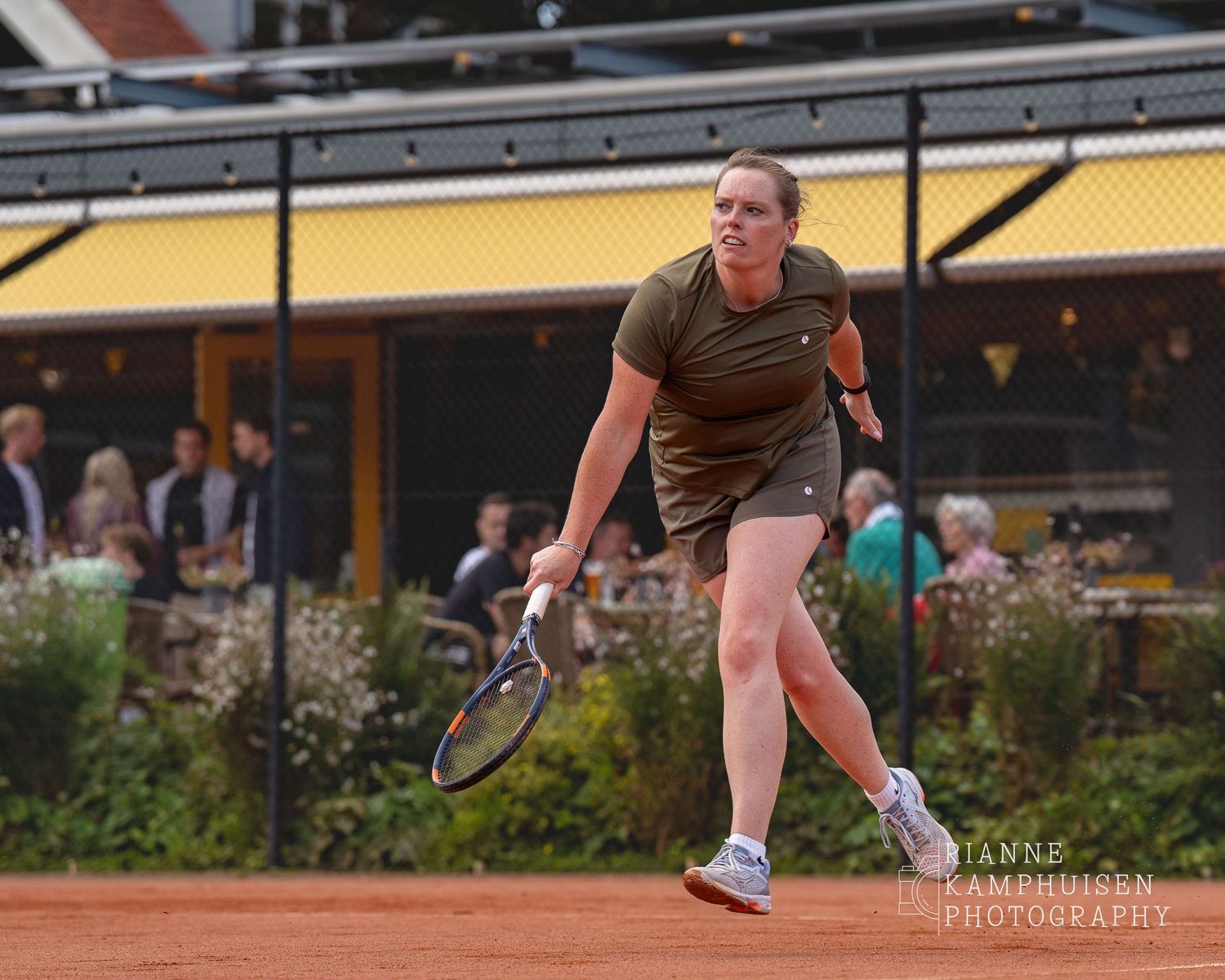 Actiefoto's van de vrijdagavond van een gravel tennistoernooi met spelers in actie, dubbelspel, toeschouwers en zomerse sfeer rond de baan.