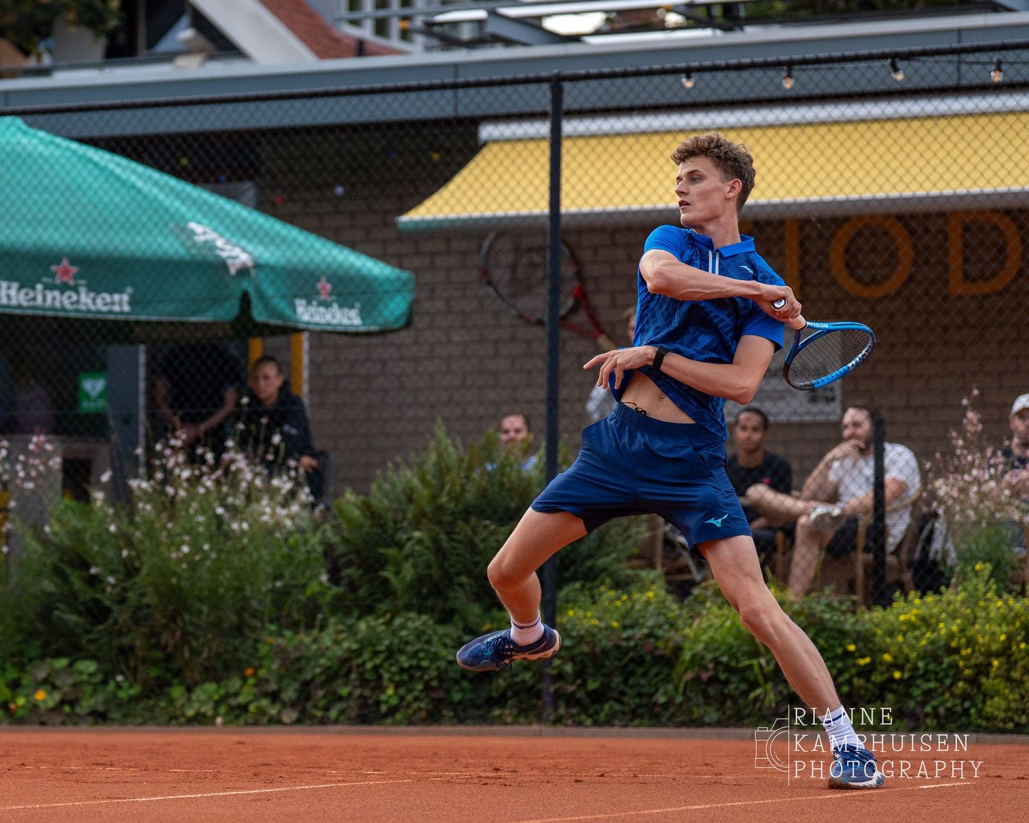 Actiefoto's van gravel tennistoernooi met spelers in actie, dubbelspel, toeschouwers en zomerse sfeer rond de baan.