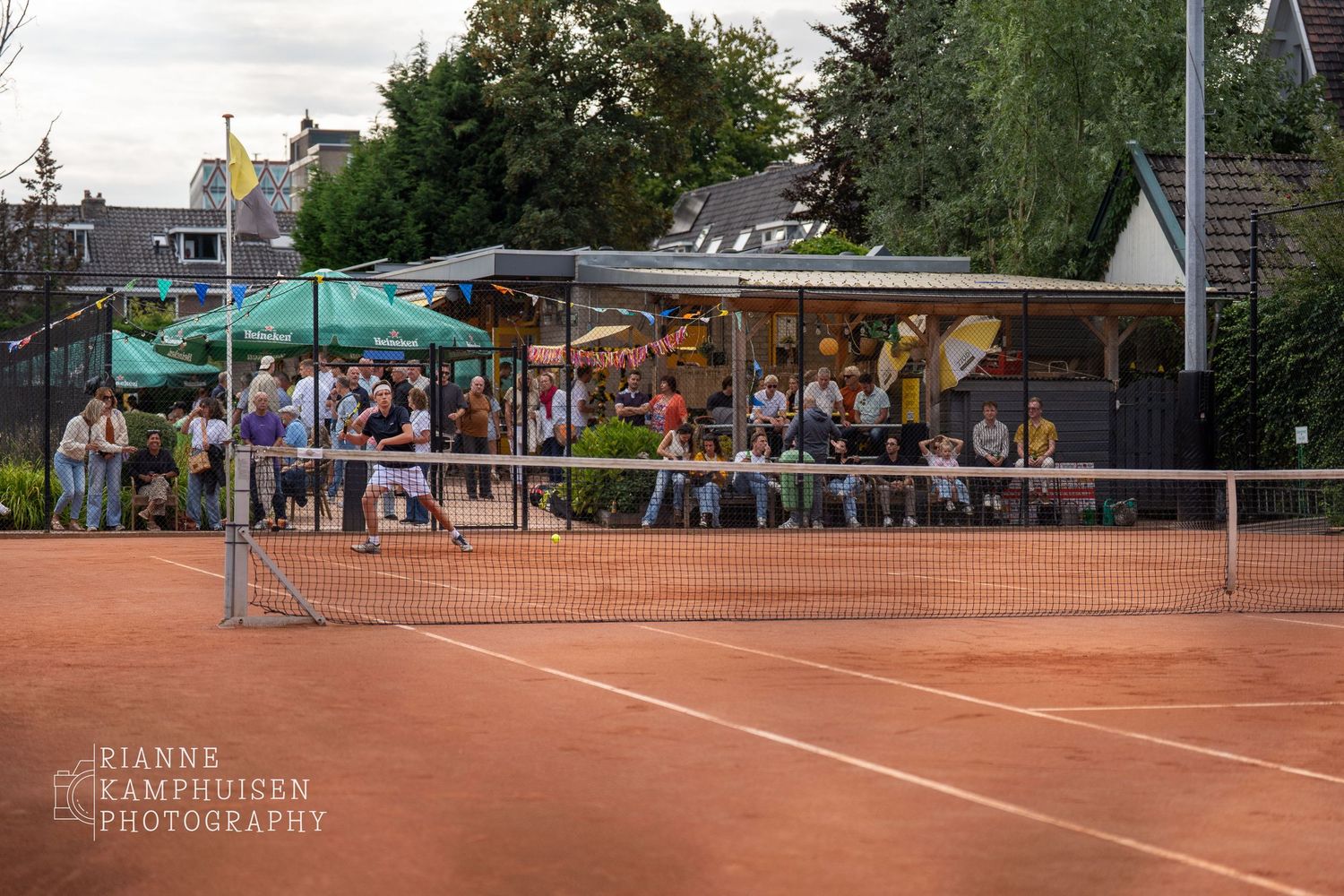 Actiefoto's en finalisten van een gravel tennistoernooi met spelers in actie, dubbelspel, toeschouwers en zomerse sfeer rond de baan.