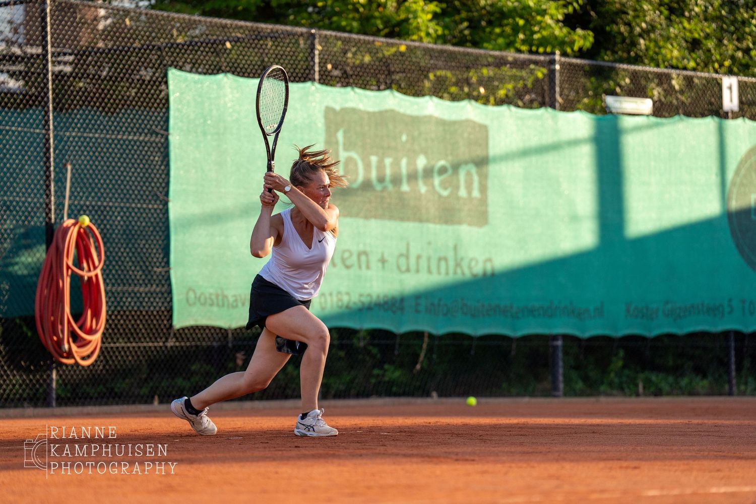 Actiefoto's van gravel tennistoernooi met spelers in actie, dubbelspel, toeschouwers en zomerse sfeer rond de baan.