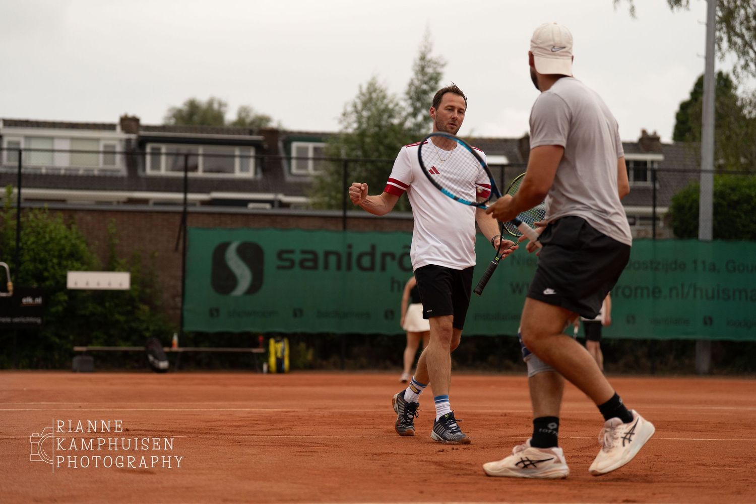 Actiefoto's en finalisten van een gravel tennistoernooi met spelers in actie, dubbelspel, toeschouwers en zomerse sfeer rond de baan.