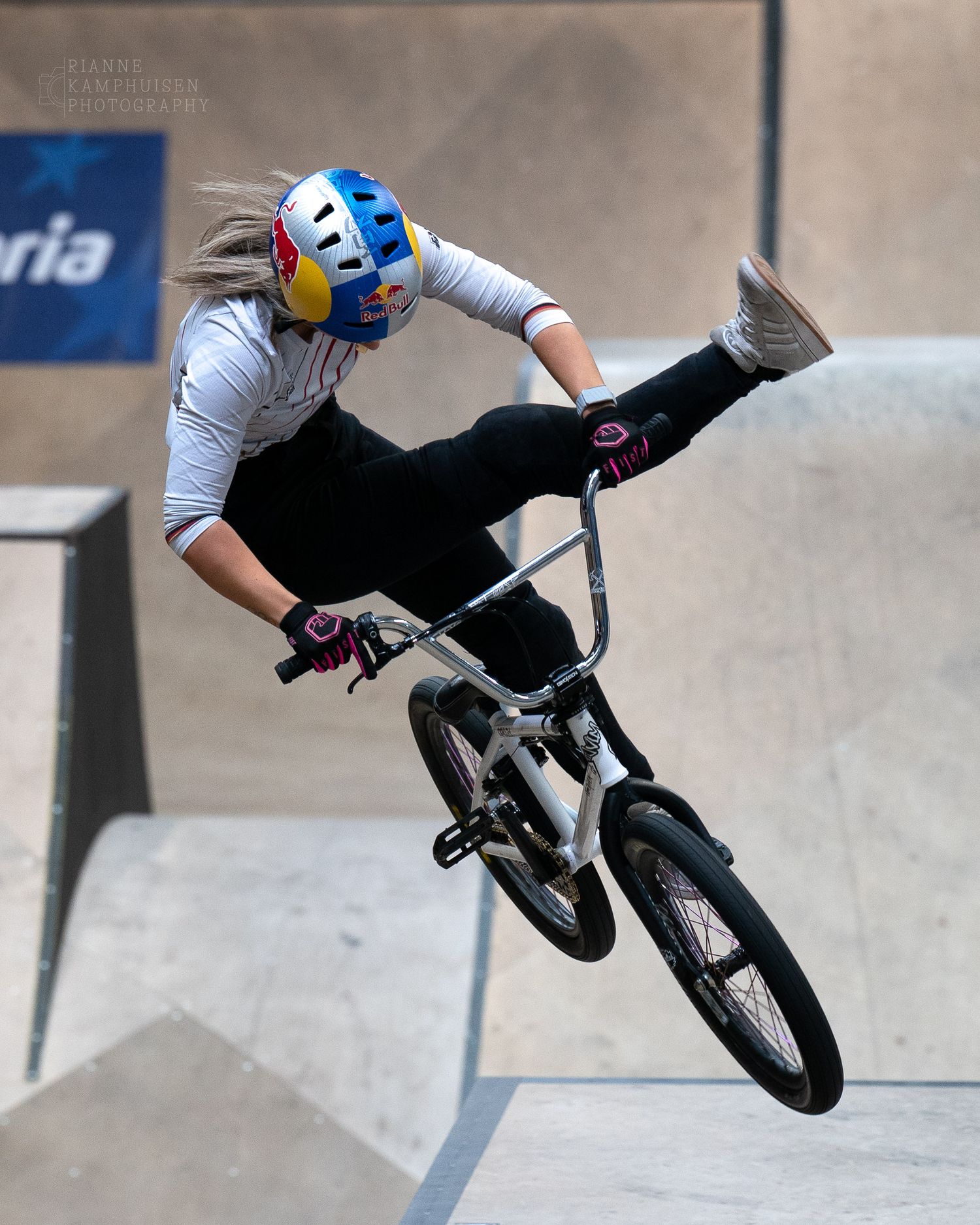 Vrouwelijke BMX rijdster doet een trick waarbij haar linkerbeen gestrekt in de lucht gaat tijden het EK BMX Freestyle