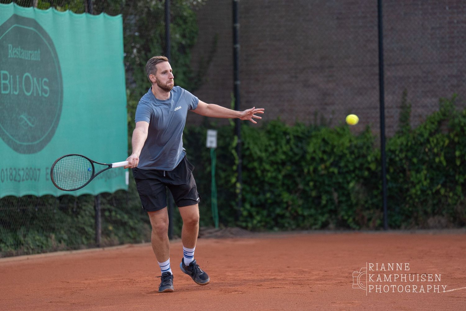 Actiefoto's van gravel tennistoernooi met spelers in actie, dubbelspel, toeschouwers en zomerse sfeer rond de baan.