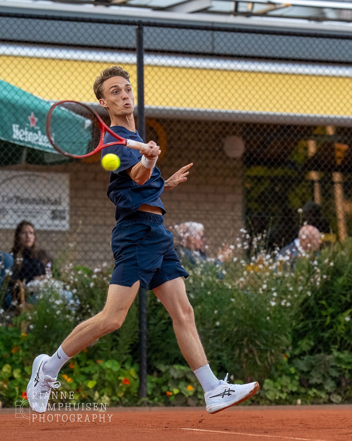 Actiefoto's van gravel tennistoernooi met spelers in actie, dubbelspel, toeschouwers en zomerse sfeer rond de baan.