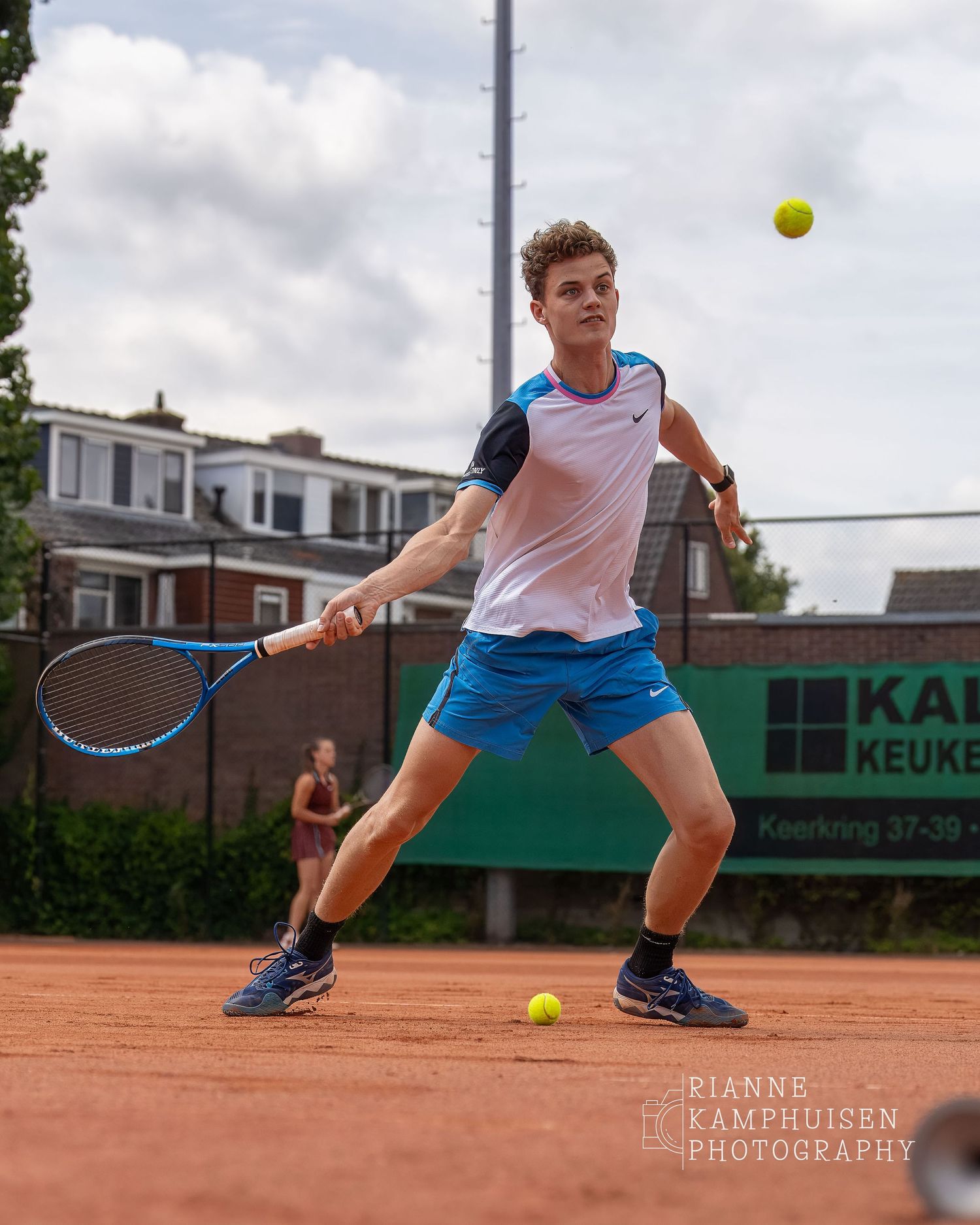 Foto van een tennisspeler vanuit een laag standpunt, de speler staat half court en slaat een drive forehand