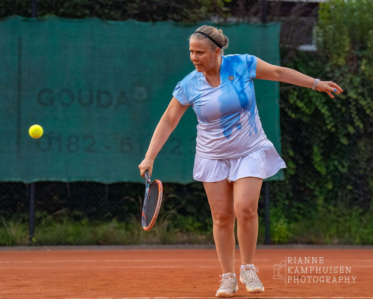 Actiefoto's van de woensdagavond van eengravel tennistoernooi met spelers in actie, dubbelspel, toeschouwers en zomerse sfeer rond de baan.