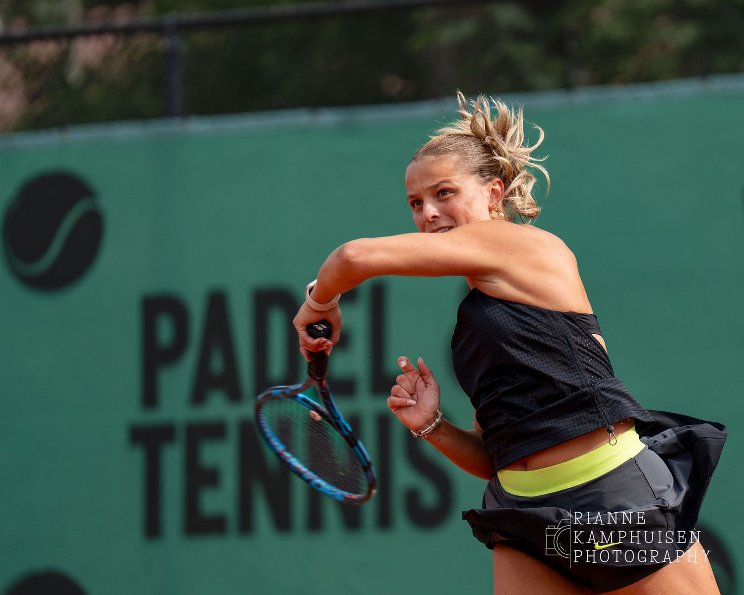 Actiefoto's van de vrijdagavond van een gravel tennistoernooi met spelers in actie, dubbelspel, toeschouwers en zomerse sfeer rond de baan.