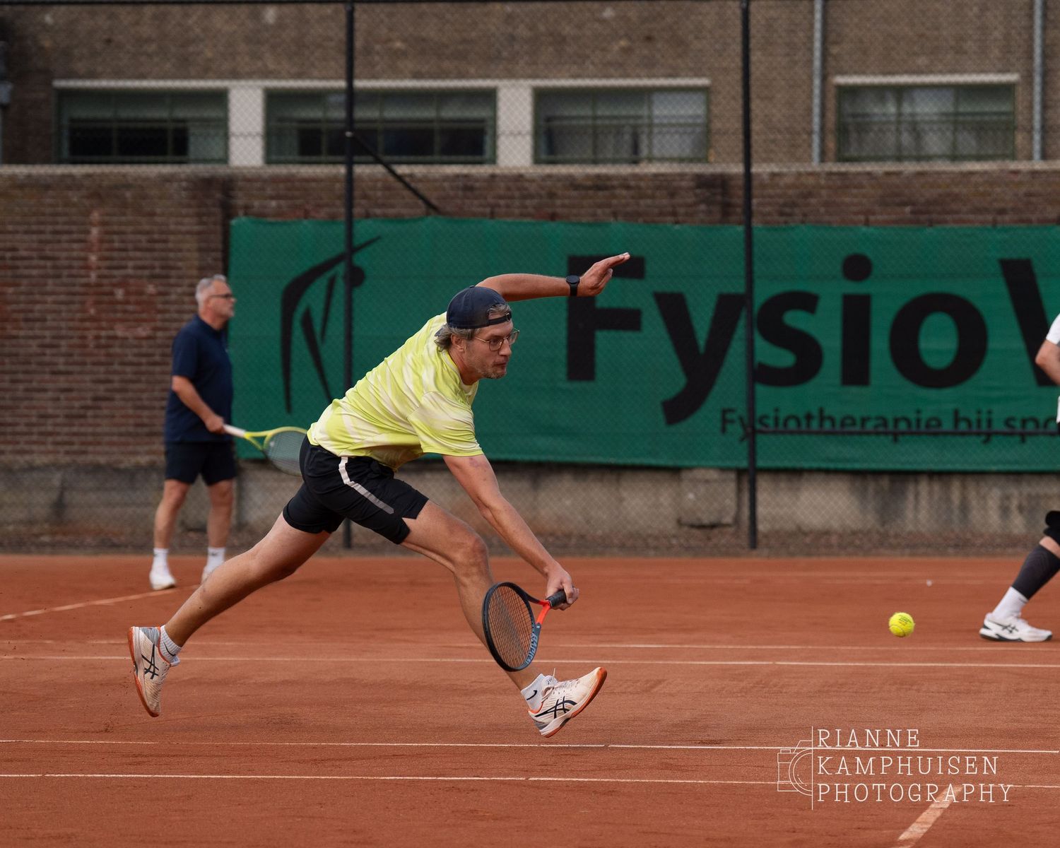 Actiefoto's van gravel tennistoernooi met spelers in actie, dubbelspel, toeschouwers en zomerse sfeer rond de baan.