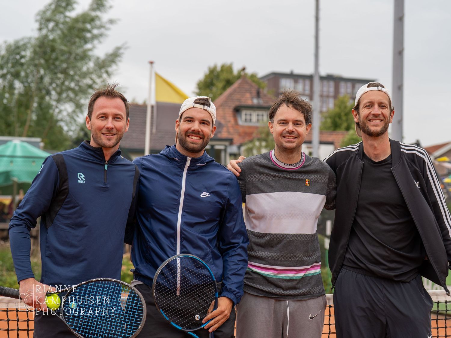 Actiefoto's en finalisten van een gravel tennistoernooi met spelers in actie, dubbelspel, toeschouwers en zomerse sfeer rond de baan.